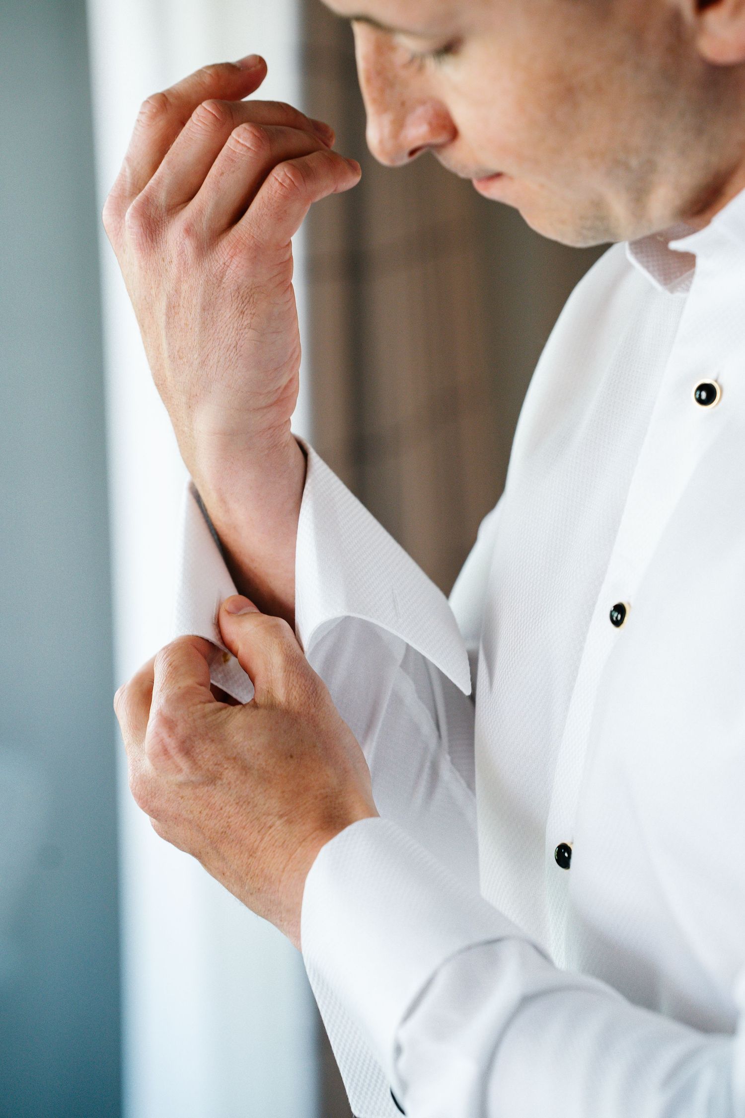 A person in a white dress shirt adjusts their collar while looking down in a series of cropped photos.