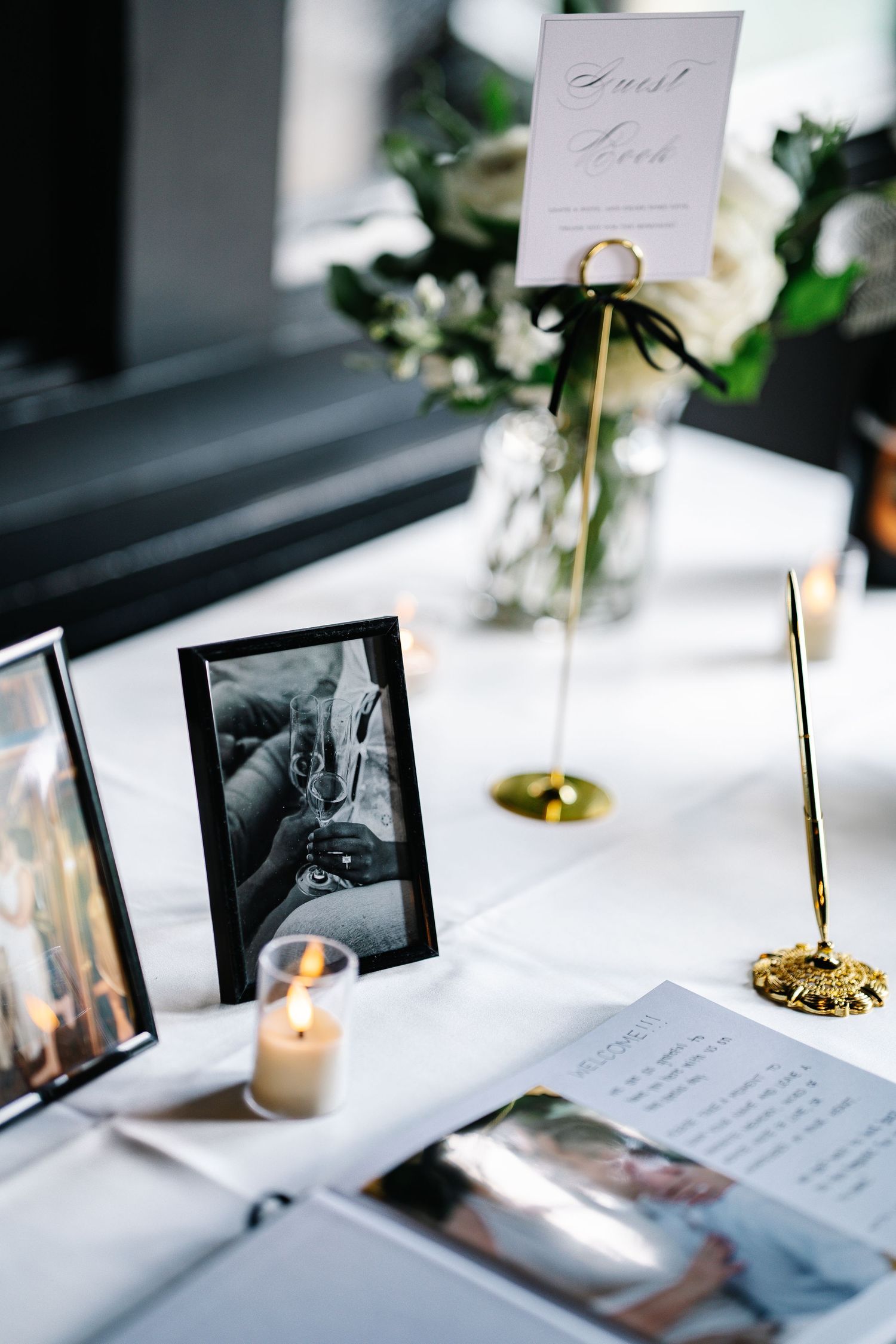 Wedding reception table setting with black and white photos, candles, and handwritten notes.