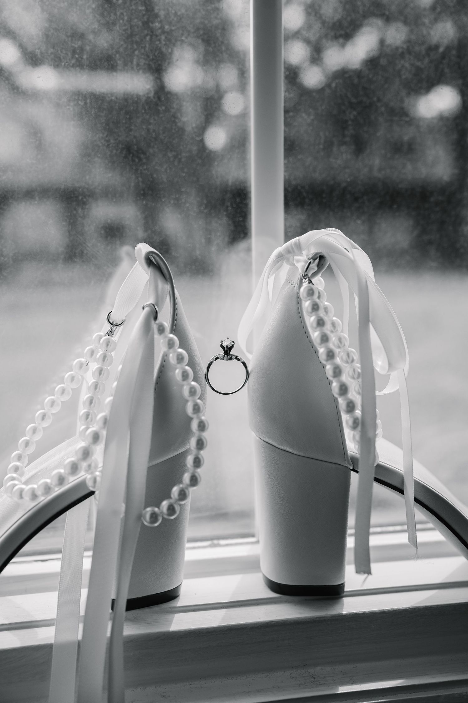 A sequence of black and white photos showing white bridal shoes with pearls and rings displayed on a windowsill.