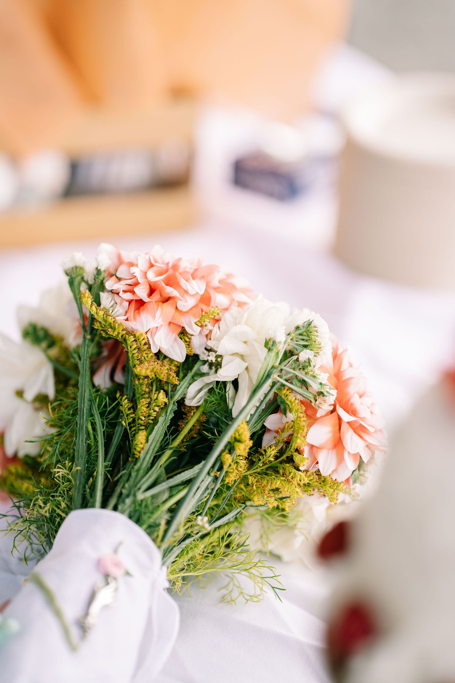 Delicate pink carnations and greenery arranged in a soft focus bouquet against a light background.