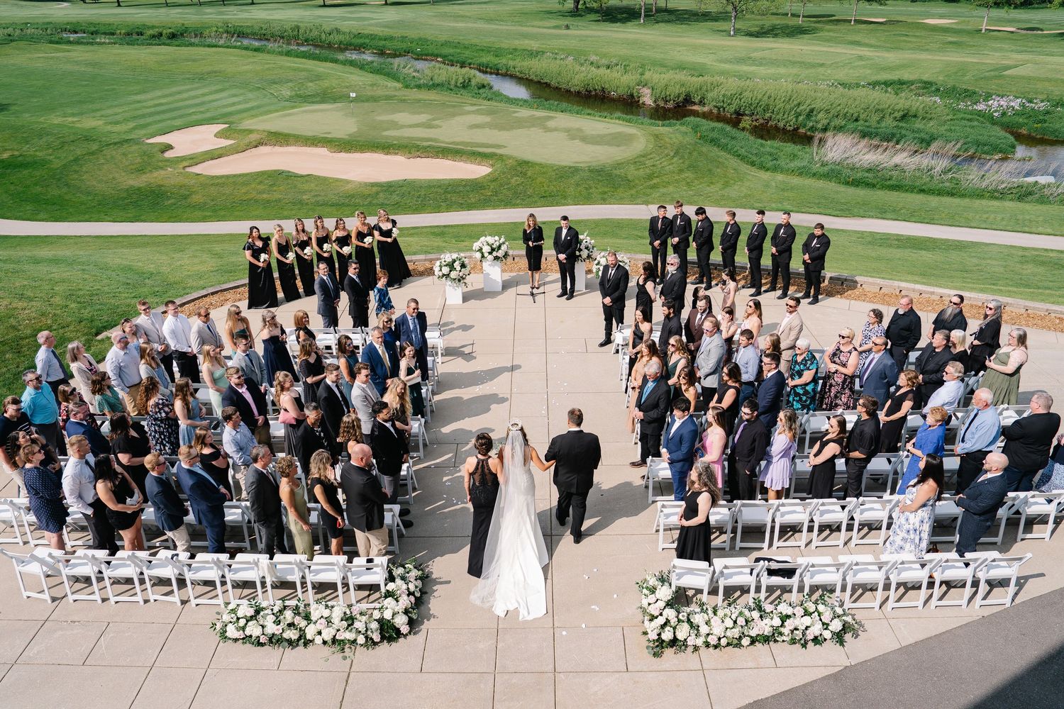 Aerial view of outdoor wedding ceremony setup with guests seated in curved rows.