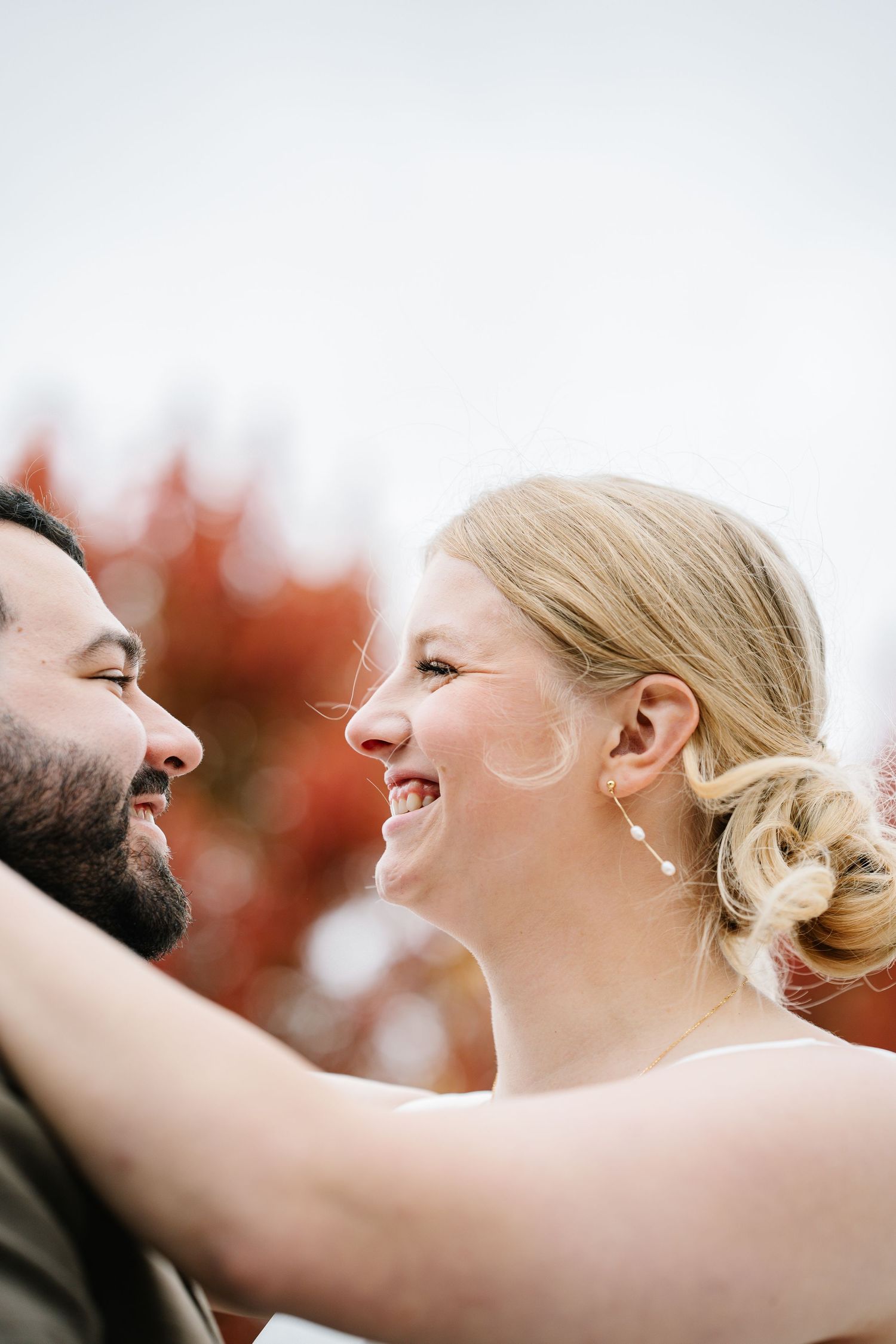 A joyful couple shares a candid laughing moment together during an outdoor autumn photoshoot.