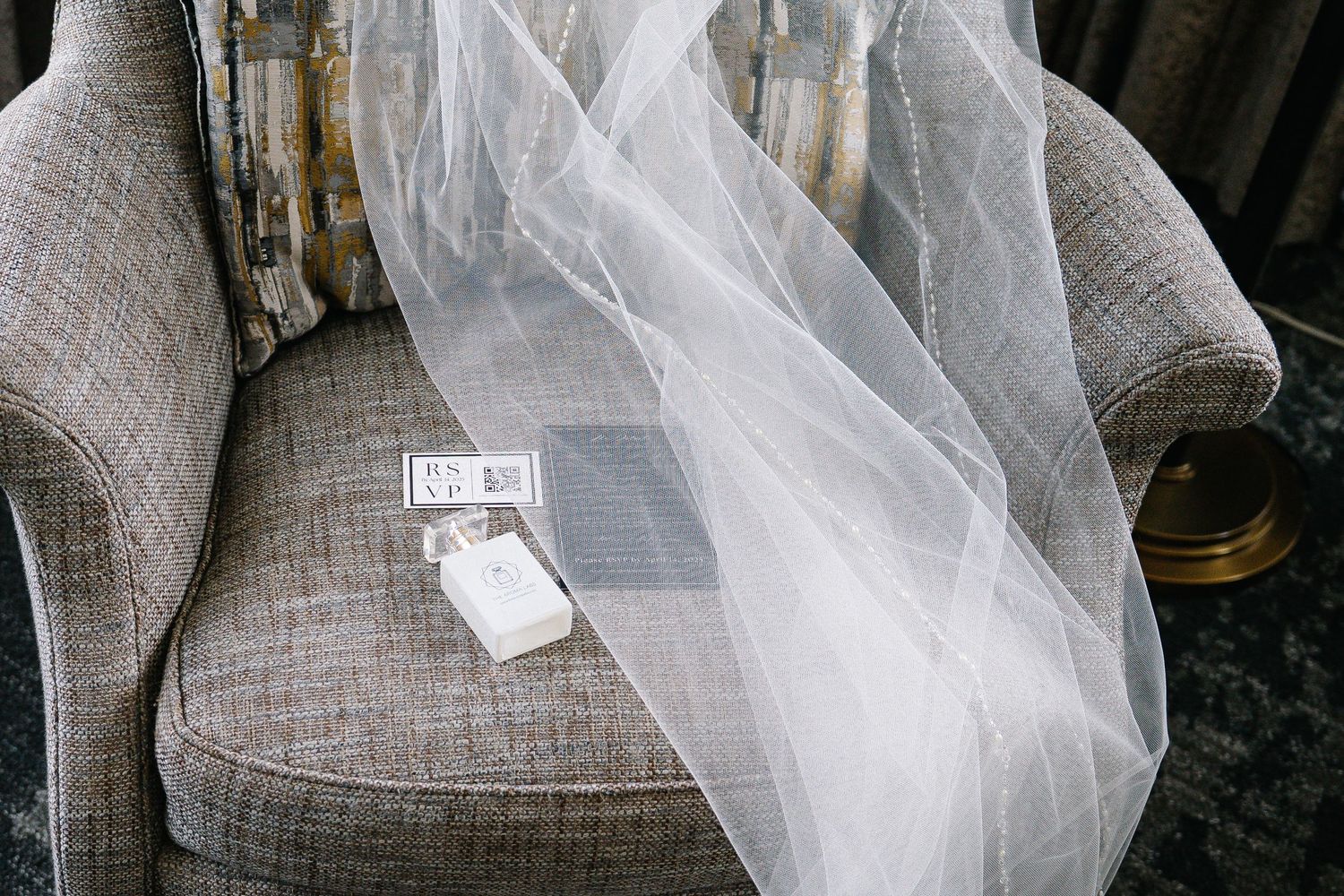 A close-up view of a light gray linen sofa with tufted details and white protective wrapping.