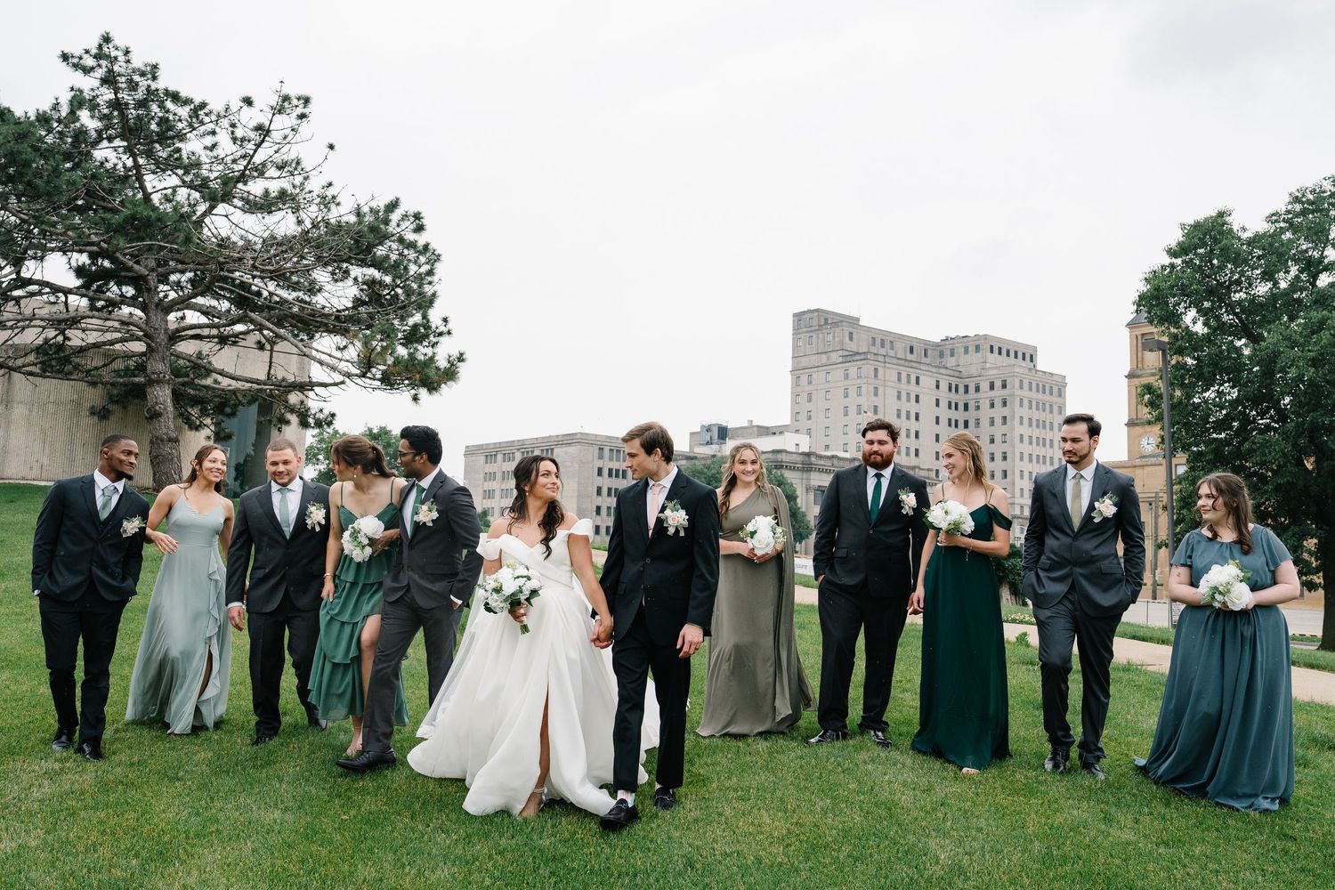 A wedding party stands on a lush green lawn during an outdoor celebration in formal attire.