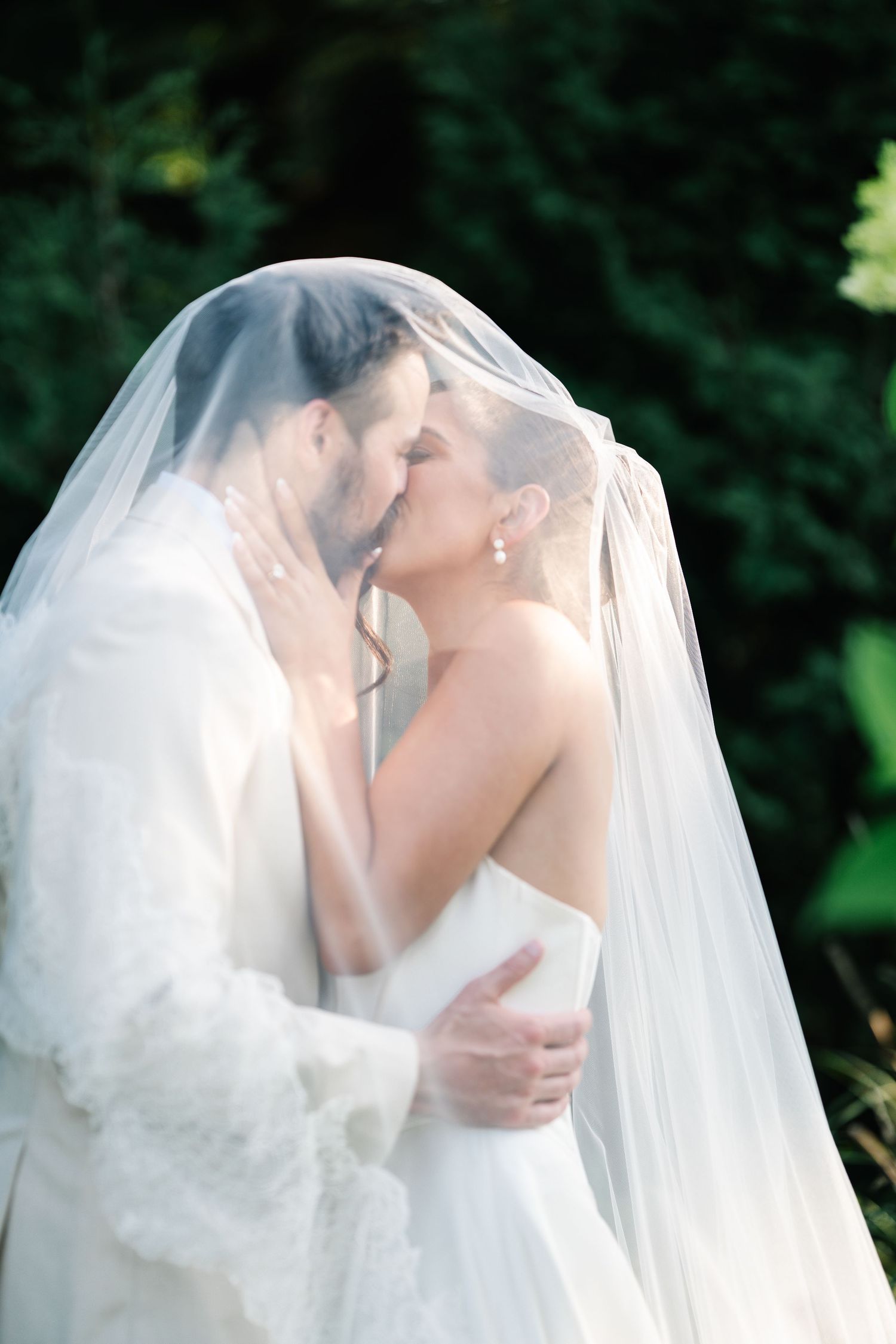 A romantic wedding sequence shows a couple sharing tender kisses under a flowing white veil in an outdoor garden setting.