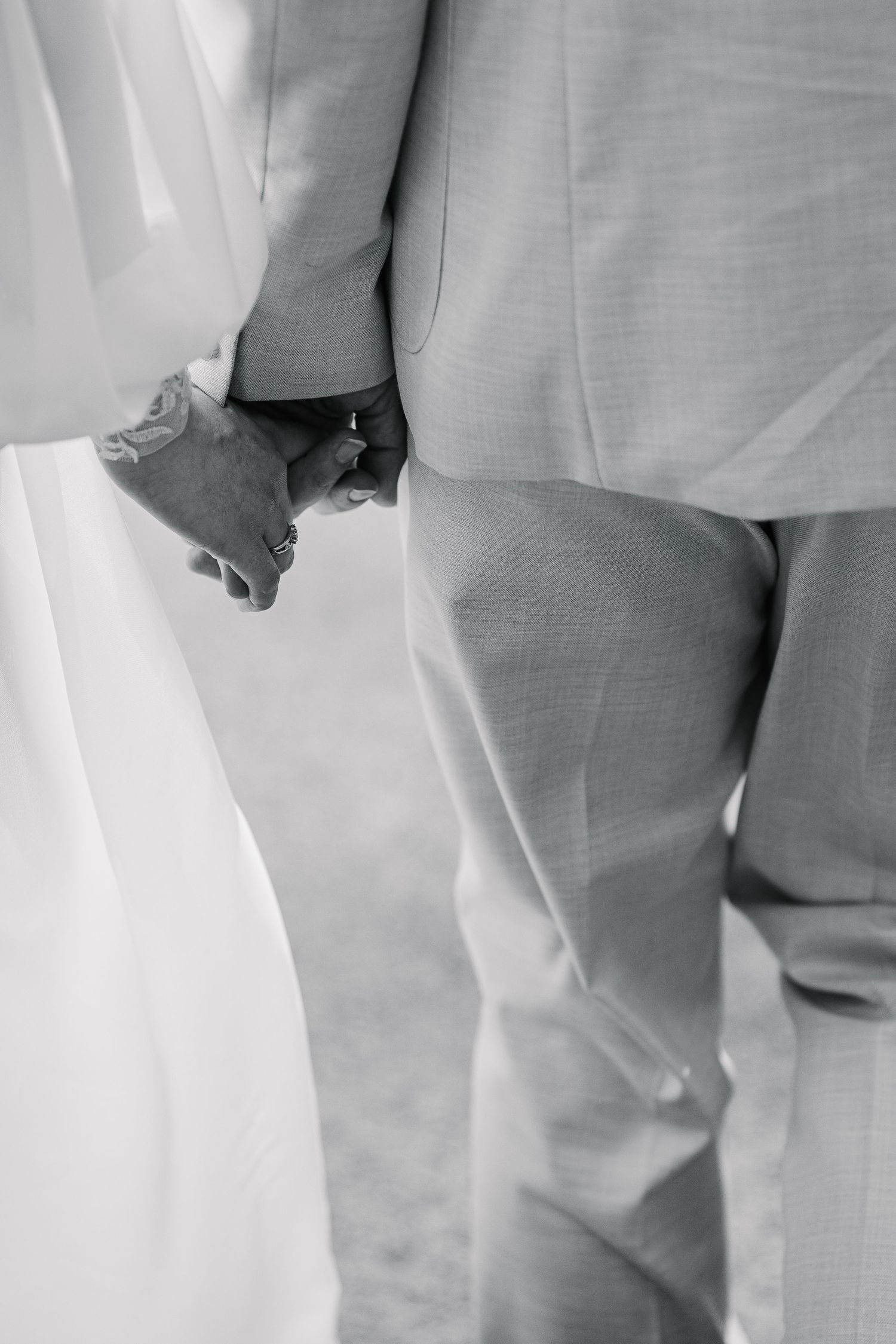 Close-up detail shot of formal attire in soft gray and white tones at a wedding ceremony.
