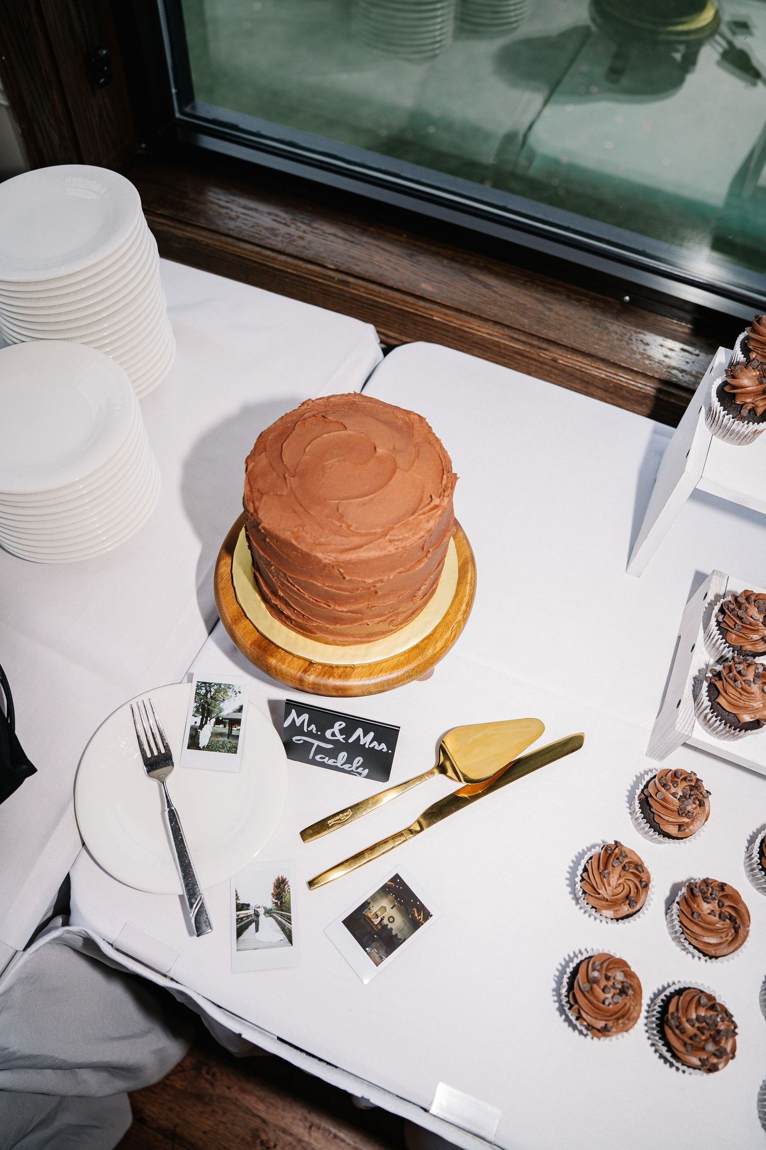A sequence of images showing the process of frosting a chocolate layer cake on a white surface with gold utensils.