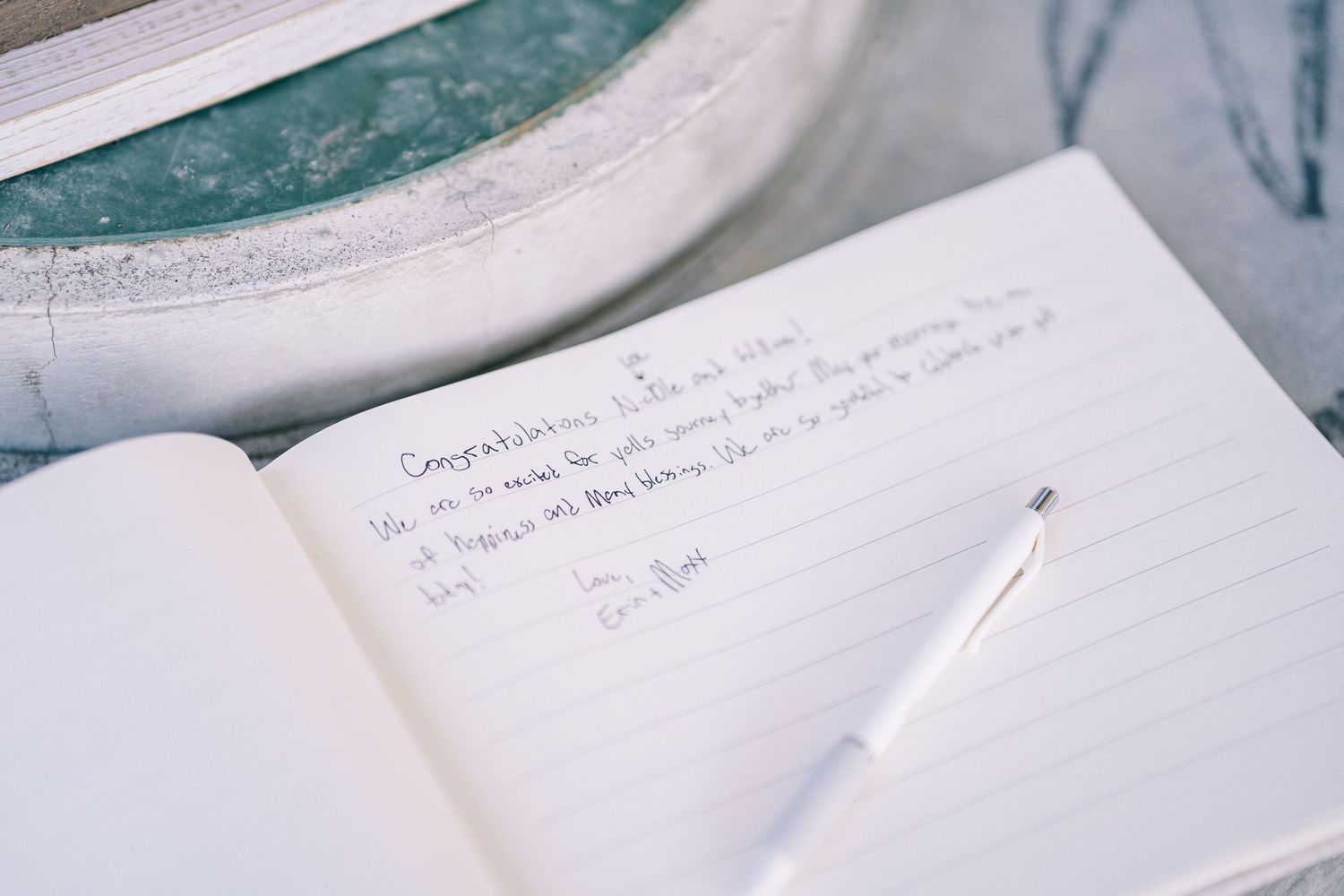 Handwritten notes on white paper with a blurred teal background showing through.