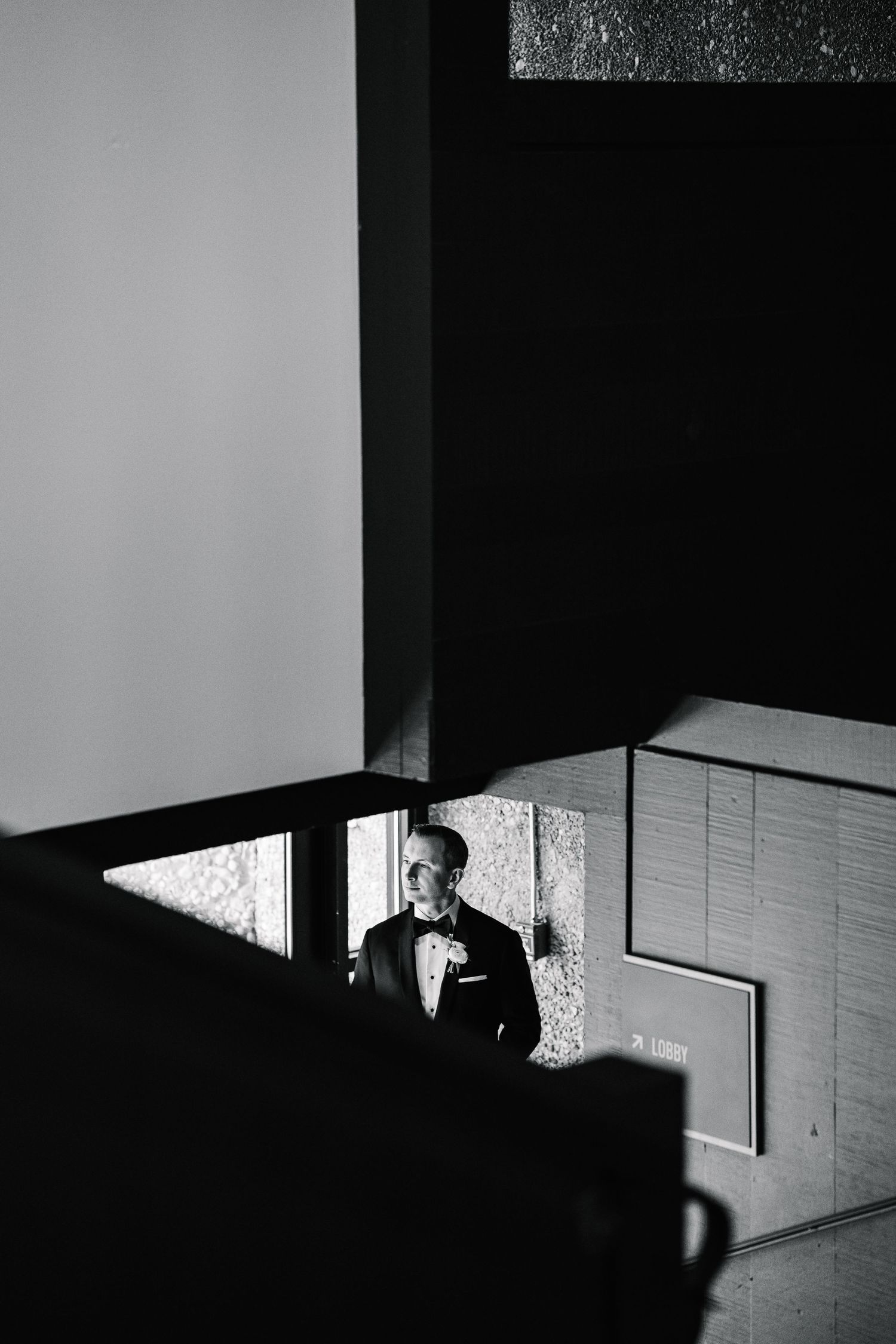 A dramatic black and white architectural photograph showing strong shadows and geometric shapes in an interior space.