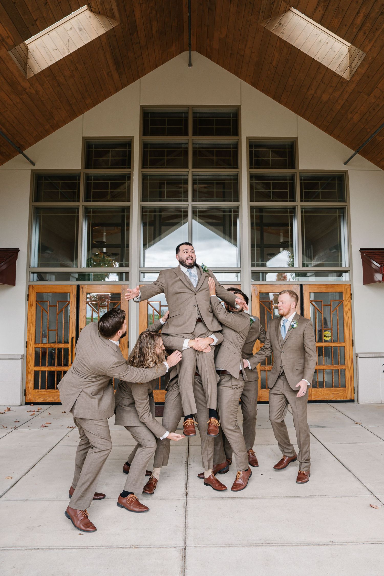 A sequence of photos showing groomsmen in tan suits performing a falling domino effect pose outside a church entrance.