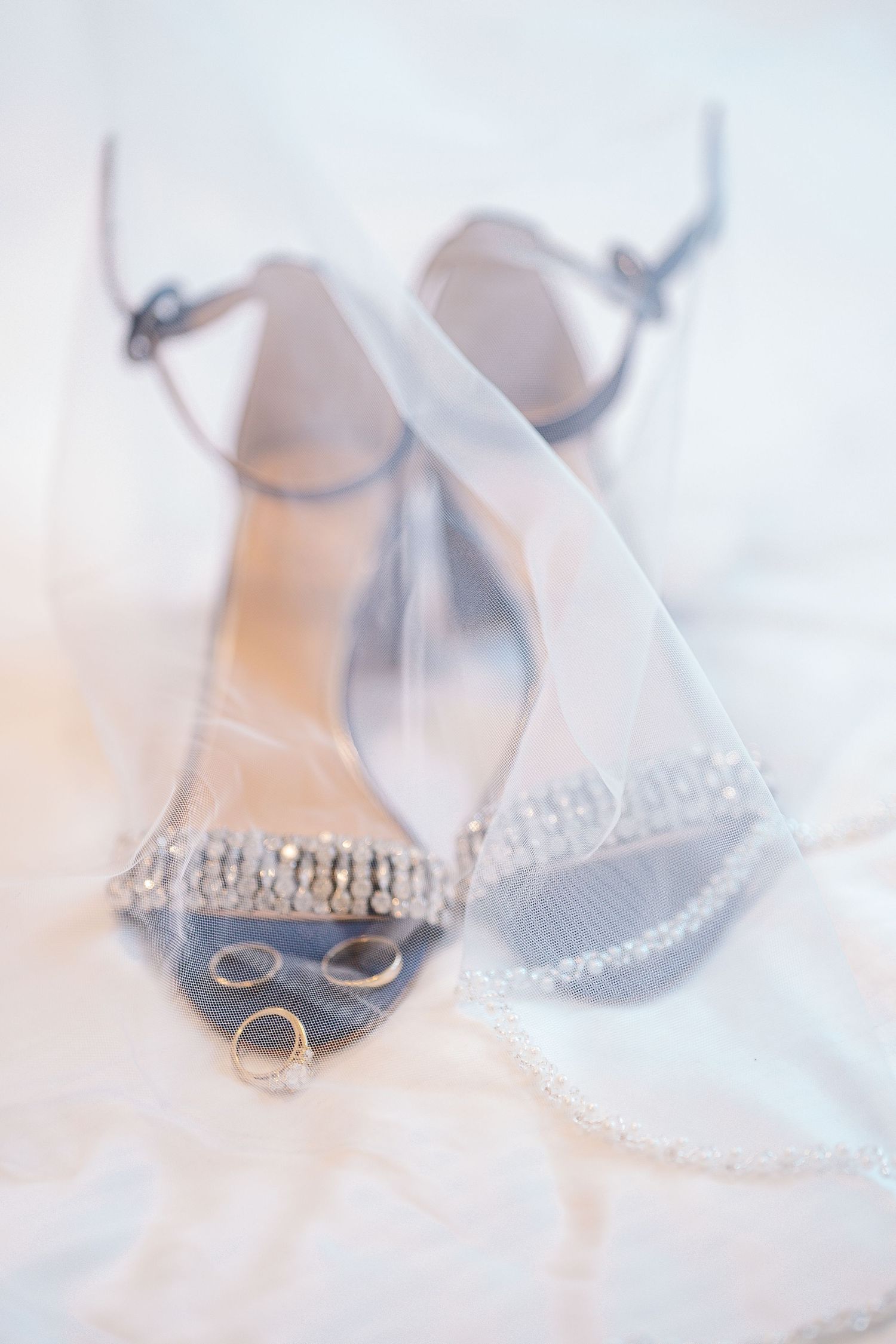 Navy blue wedding shoes with crystal details rest elegantly on white tulle fabric.