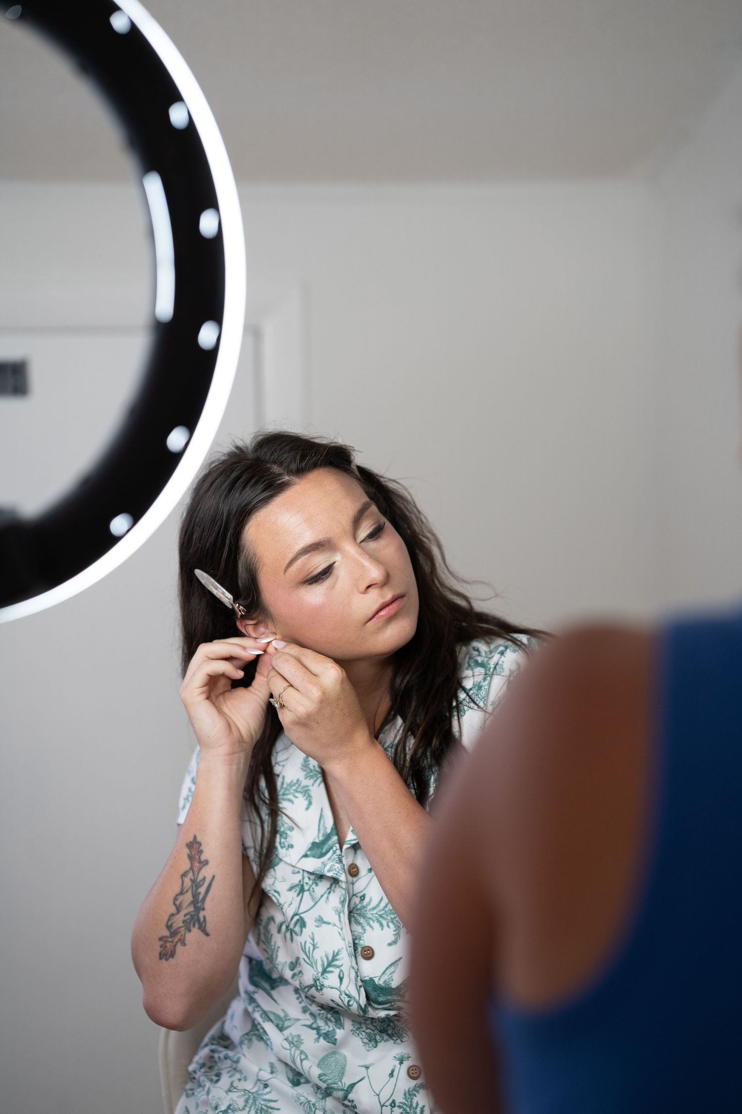 A person wearing a floral print top poses against a light background with a ring light visible in multiple shots.