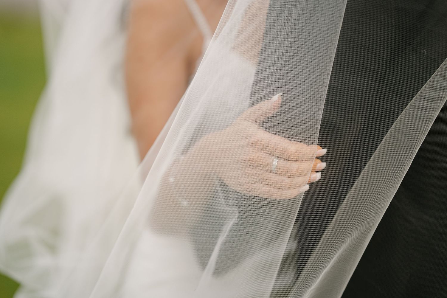 Close-up detail of flowing white wedding veil fabric with soft light filtering through.