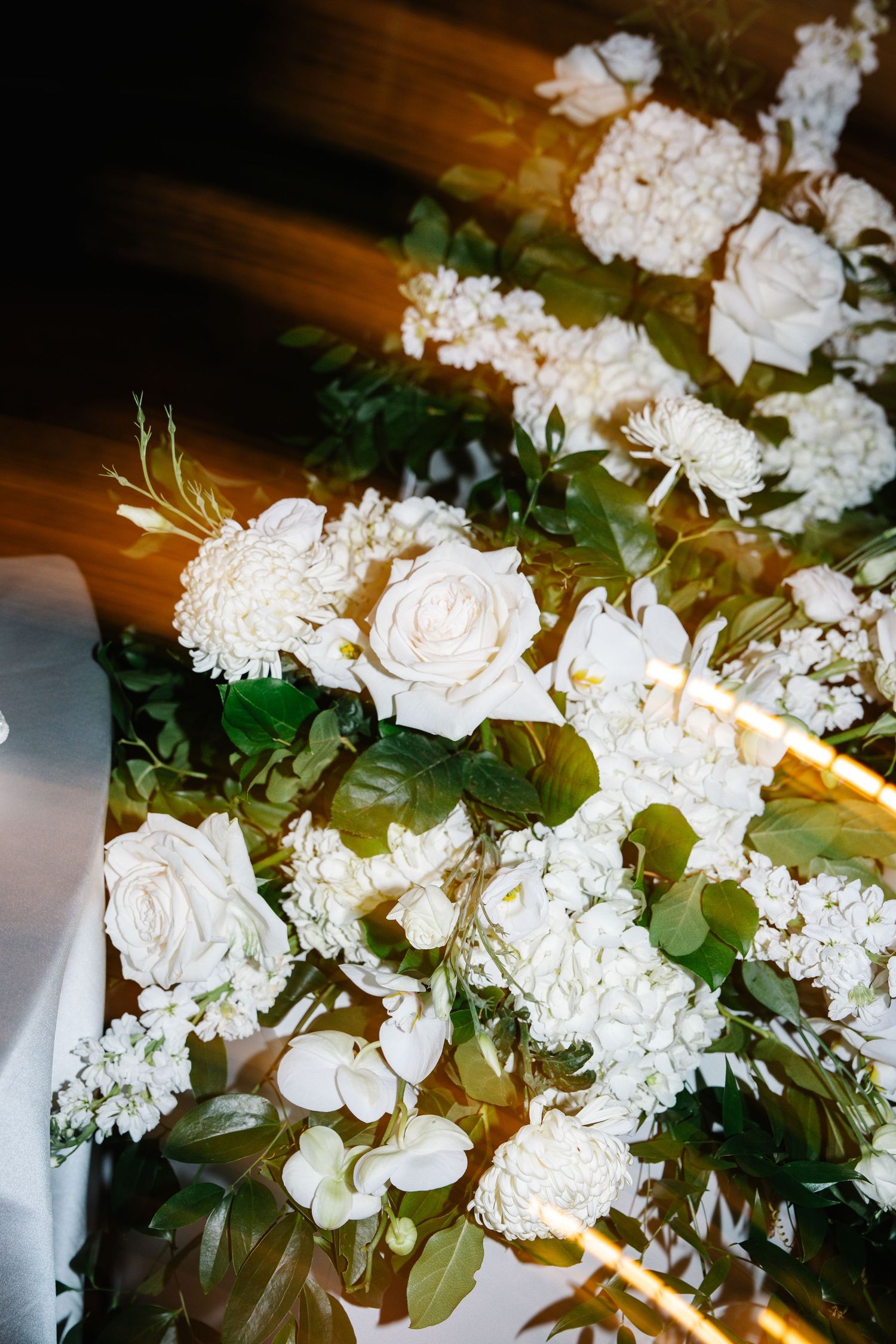 A close-up view of white roses and hydrangeas arranged in an elegant floral display with lush green foliage.