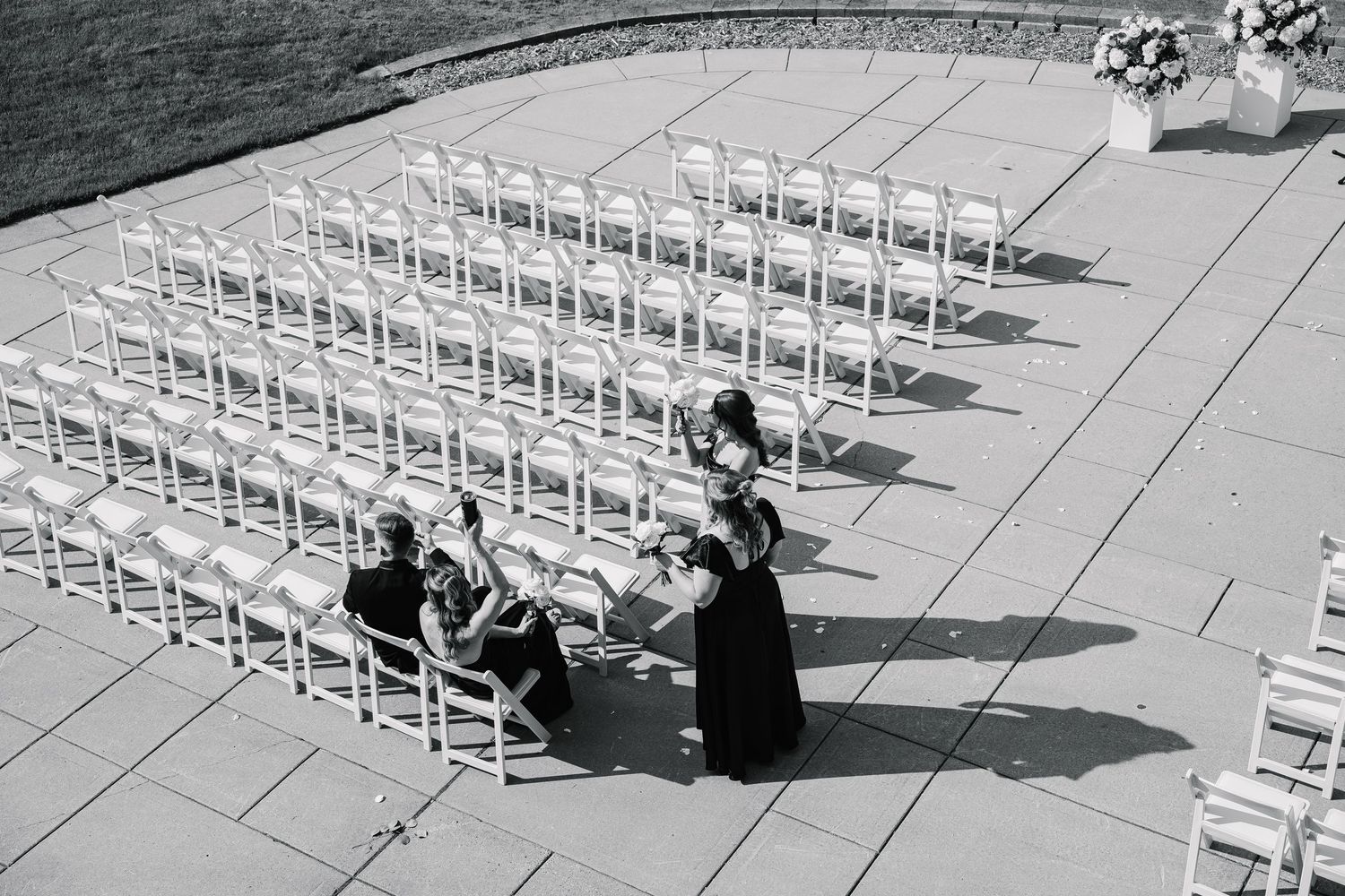 Sequence of figures setting up rows of white folding chairs in an outdoor venue for an event.
