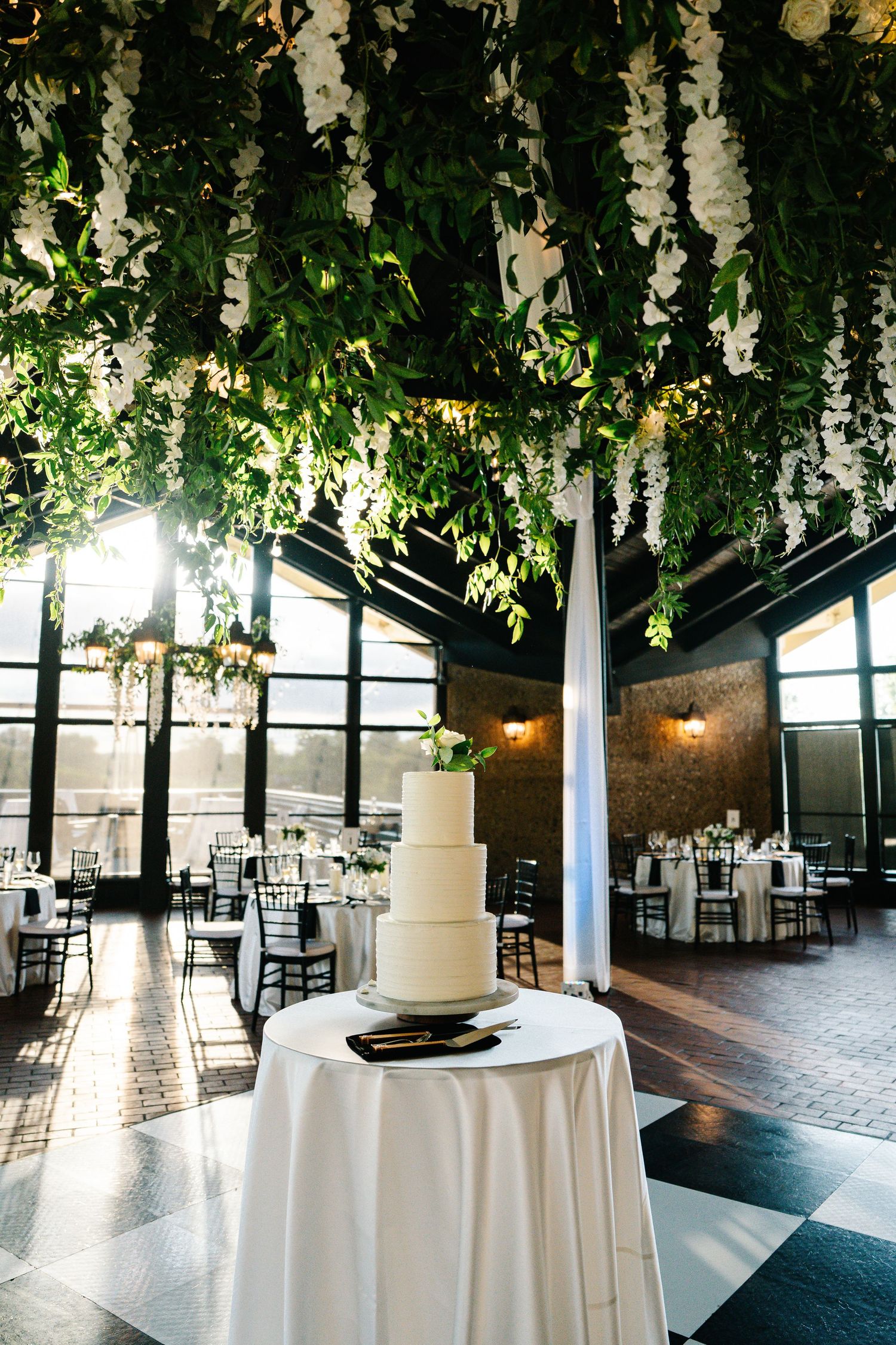 Wedding reception venue decorated with elegant white drapes and hanging greenery creates a romantic atmosphere.