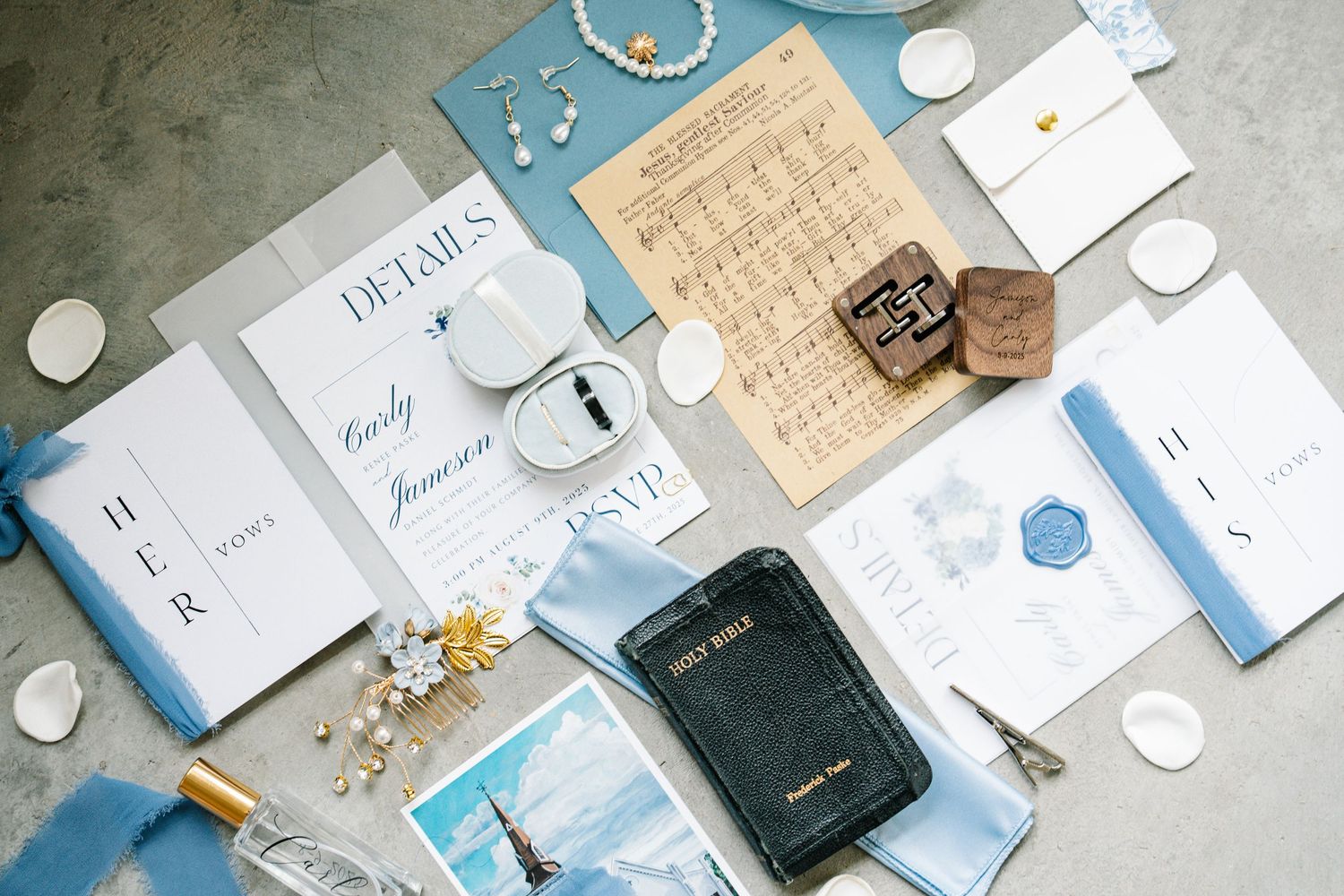 Flat lay of wedding stationery items including blue and white invitations, envelopes, and decorative elements on a light surface.