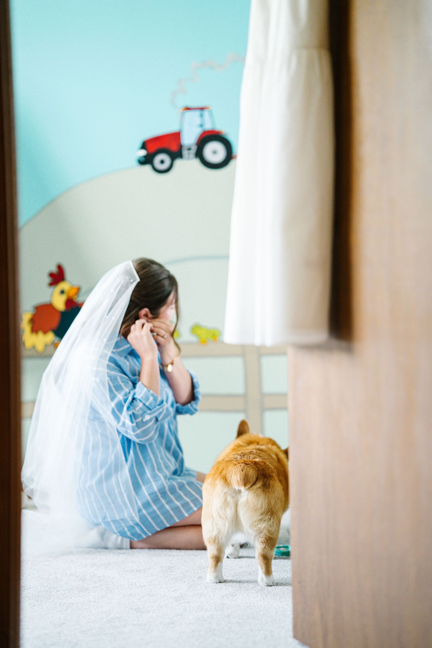 Cat approaches someone lying on white floor in striped pajamas while toy tractor is visible in background.