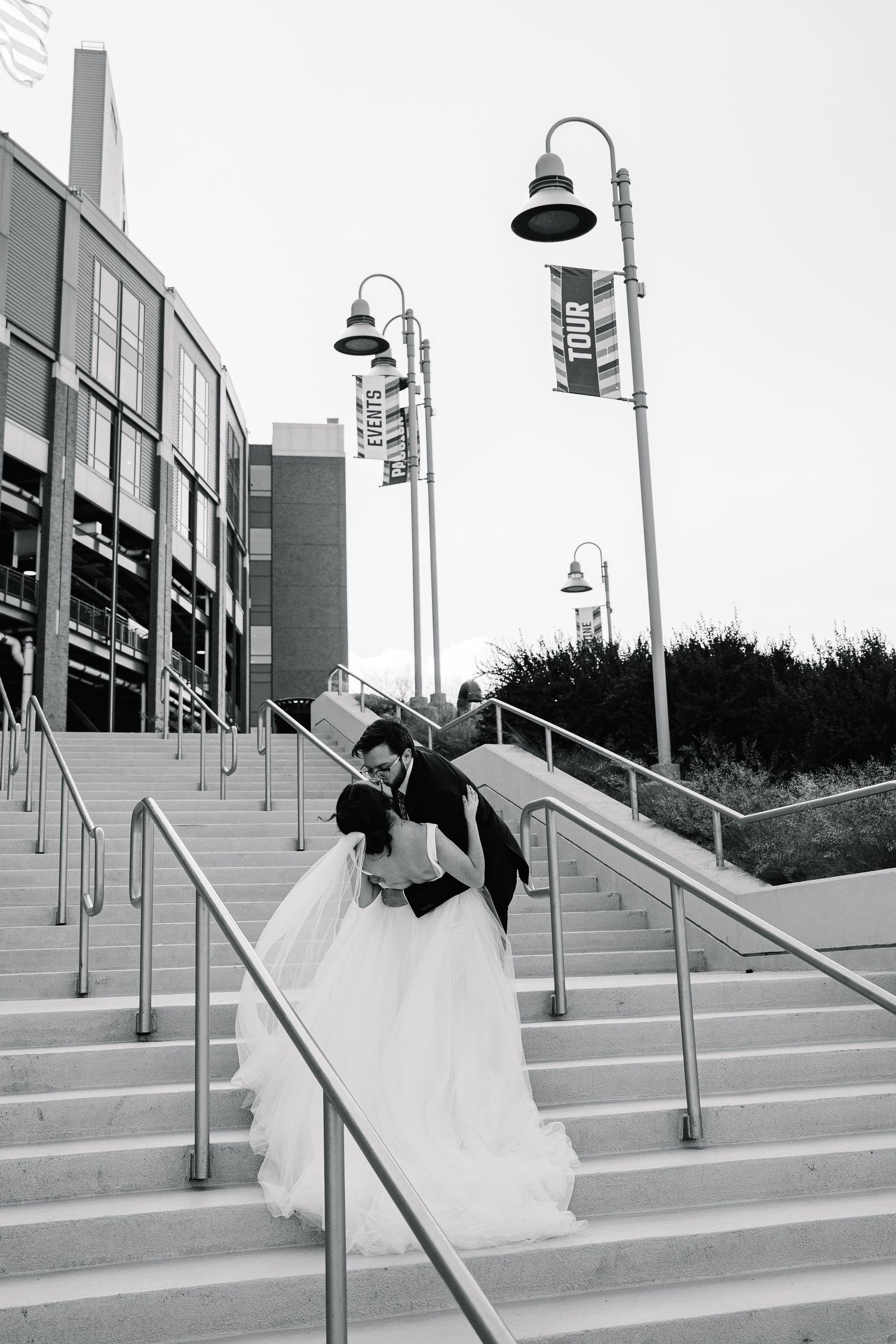 Black and white sequence of newlyweds descending concrete steps with bride's dress flowing.