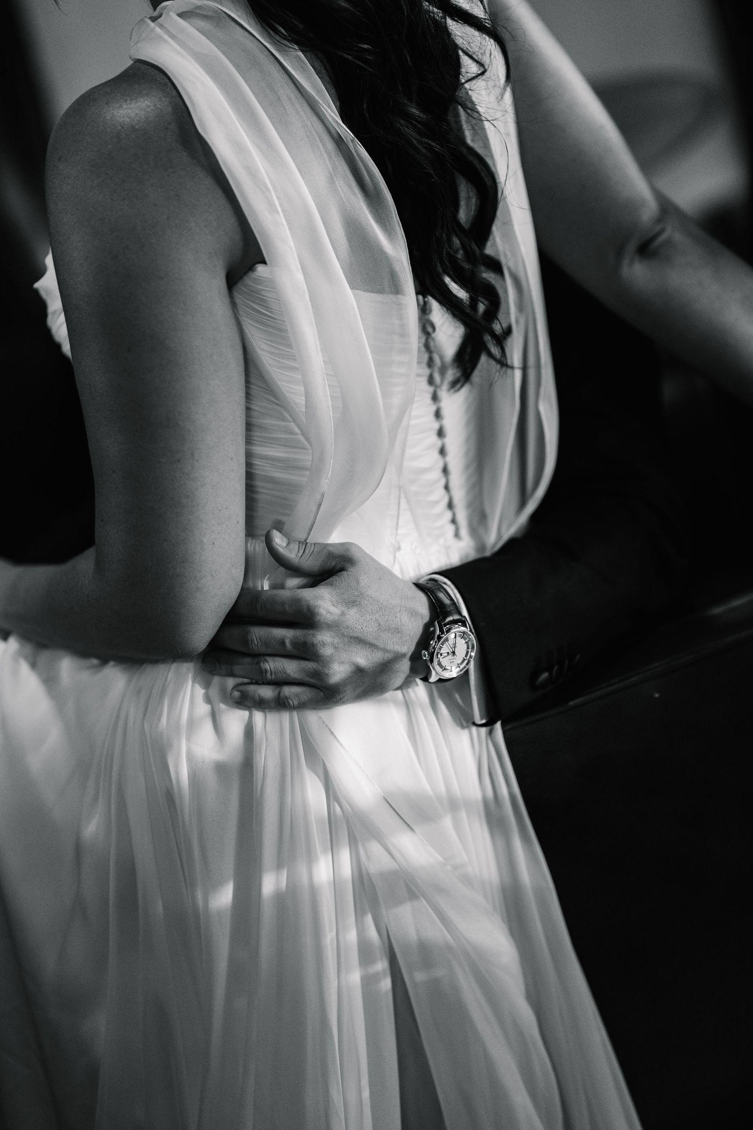 Black and white series of images showing the delicate details of a white wedding dress with flowing fabric and pleats.