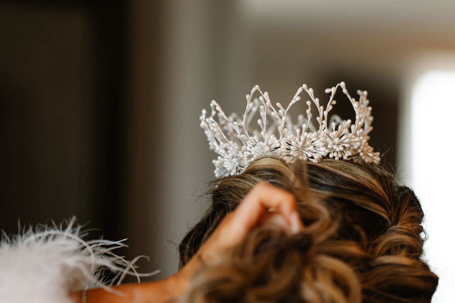 A sparkling silver tiara crown with delicate crystal details sits elegantly against a blurred background.