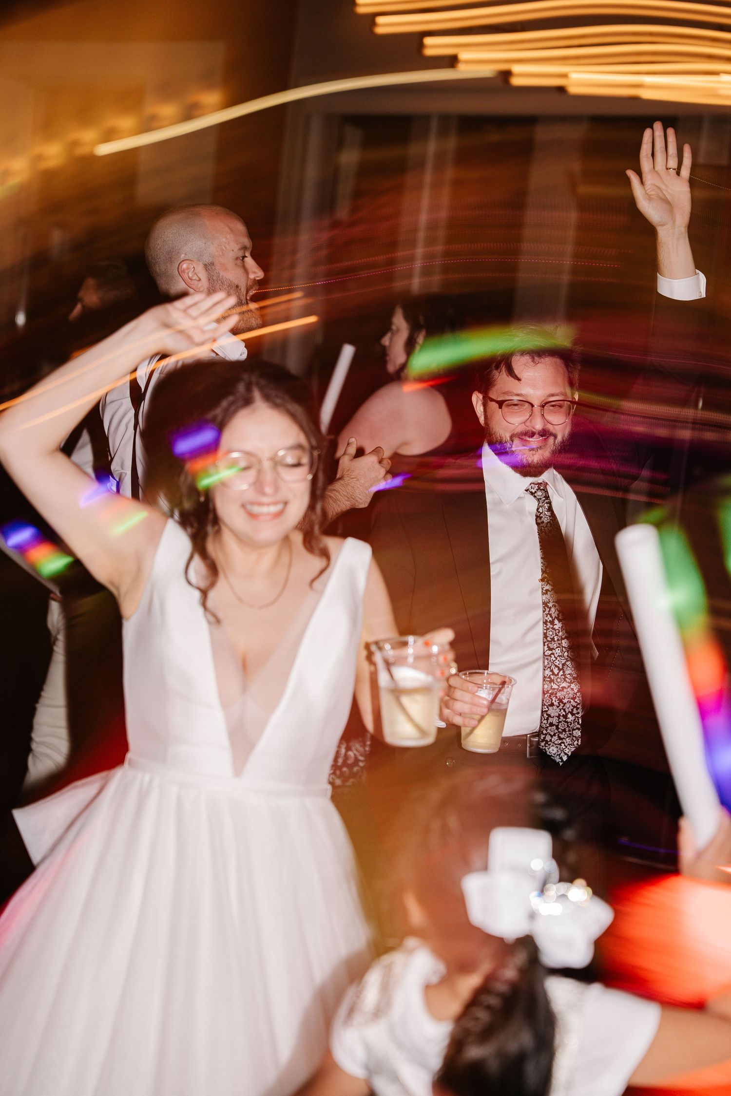 Wedding reception dance party with colorful lights and joyful celebration.