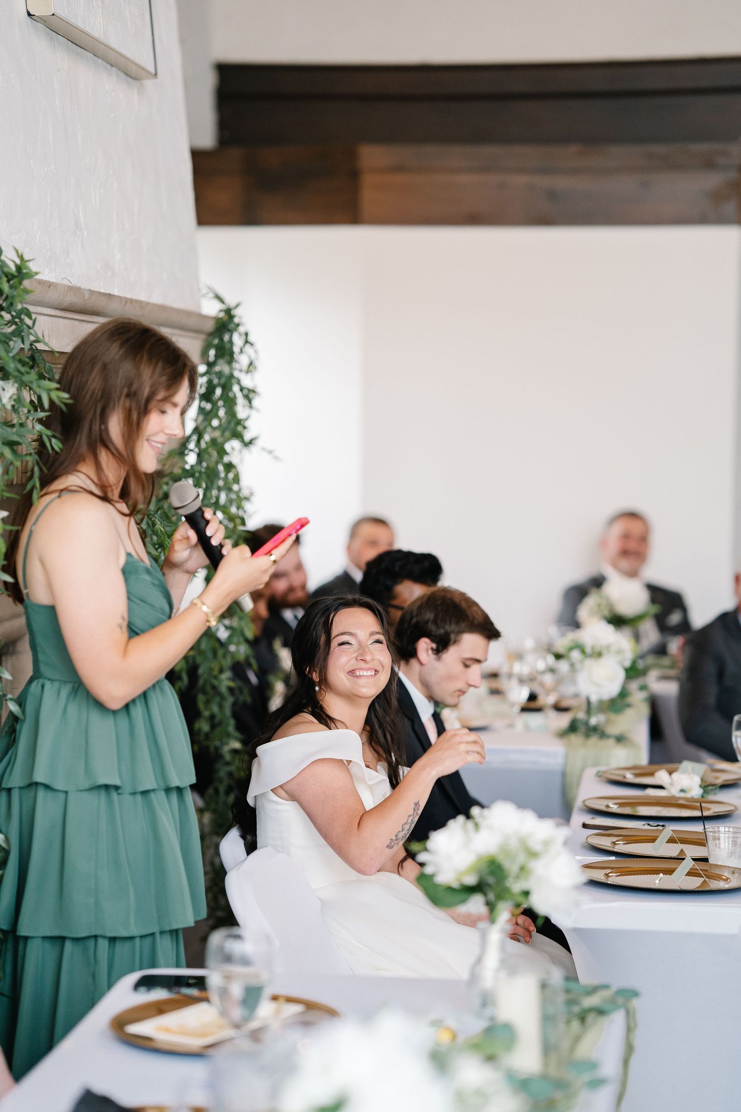 Wedding guests enjoy a reception dinner at elegantly decorated tables with green and white decor.