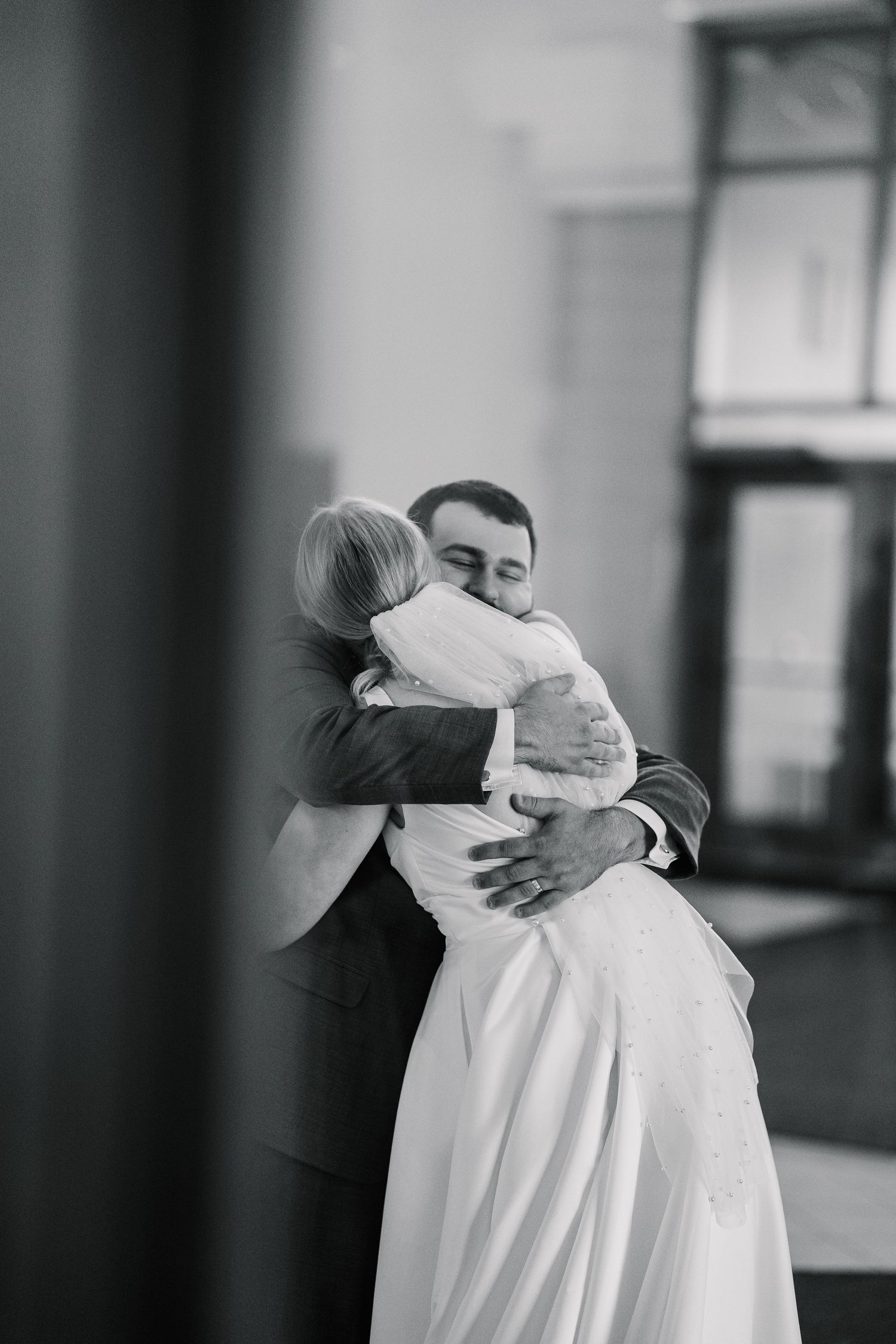Two people share an intimate embrace in black and white, with soft lighting creating a tender emotional moment.