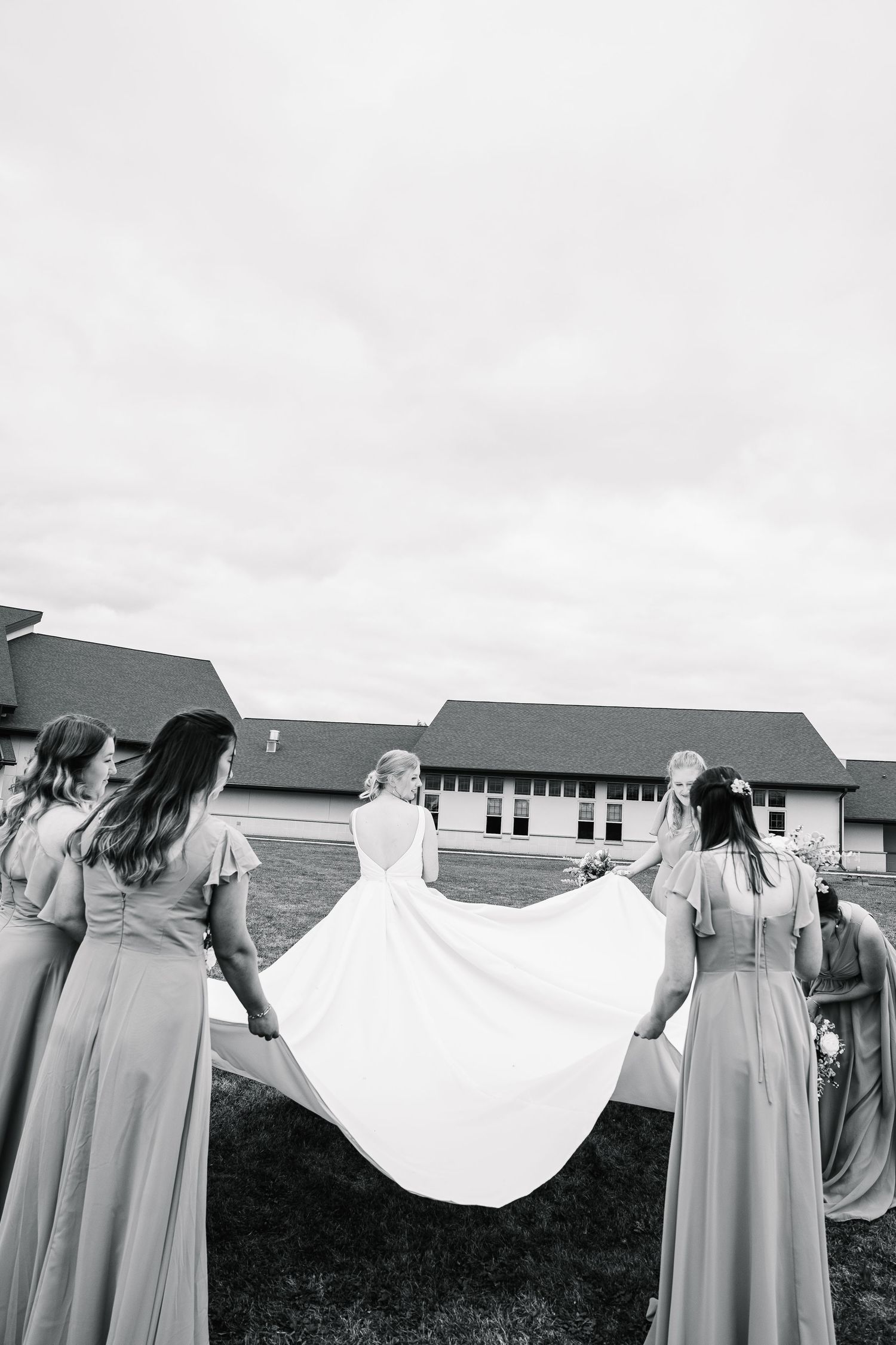 A series of black and white photos showing bridesmaids in light colored dresses holding a flowing white veil in the wind.