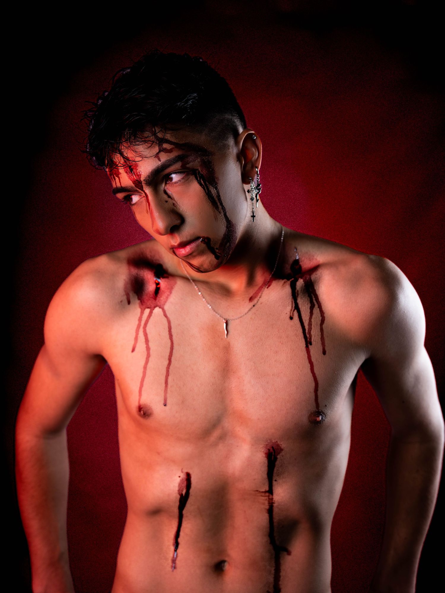 Artistic photo of torso with theatrical blood makeup against dark red backdrop.