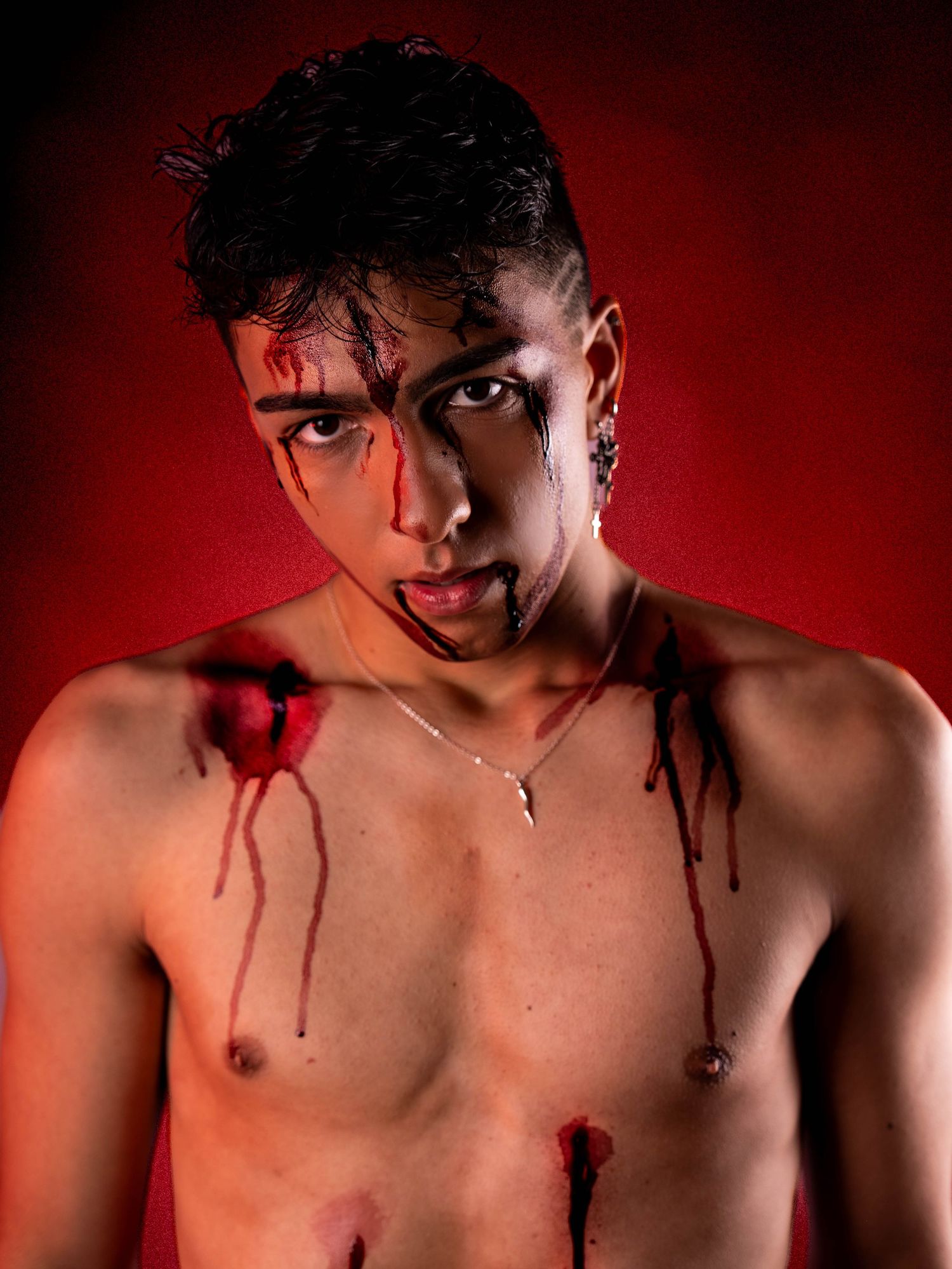 Close-up portrait with theatrical blood effects in dramatic red lighting.