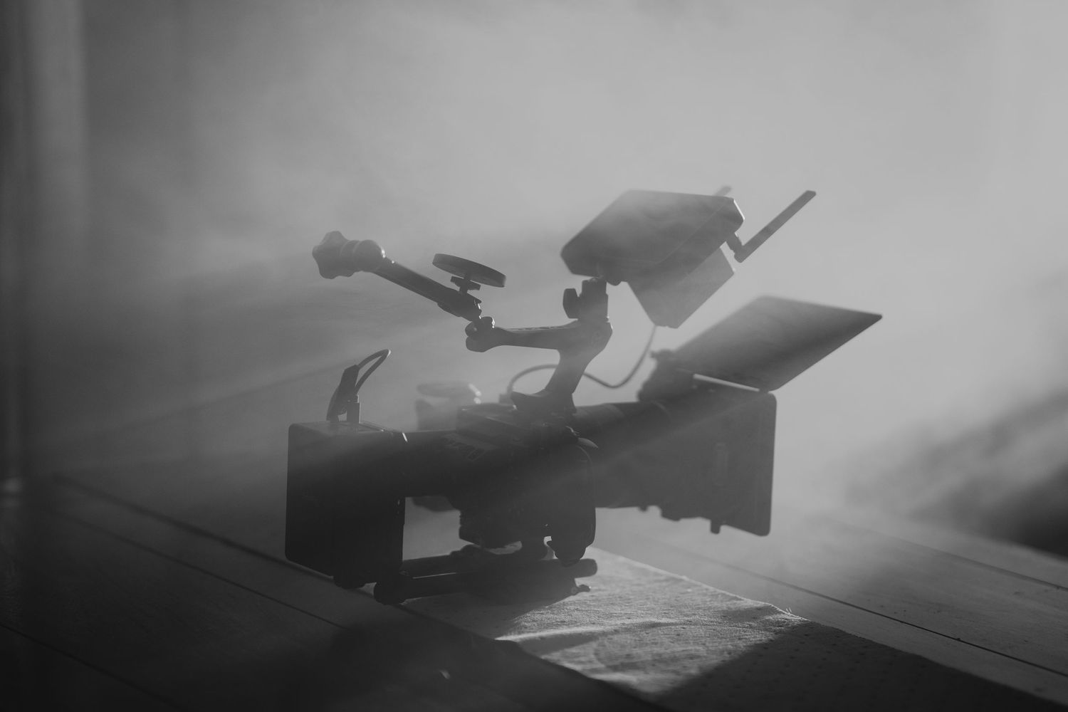 Grayscale industrial scene with equipment silhouettes in foggy atmosphere.