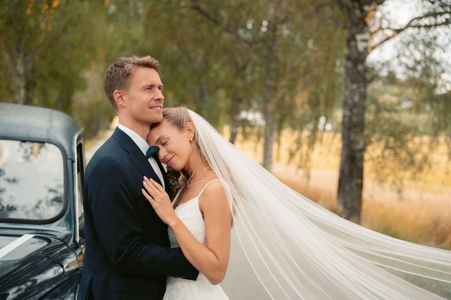 Wedding couple poses together in romantic outdoor setting with soft natural lighting.