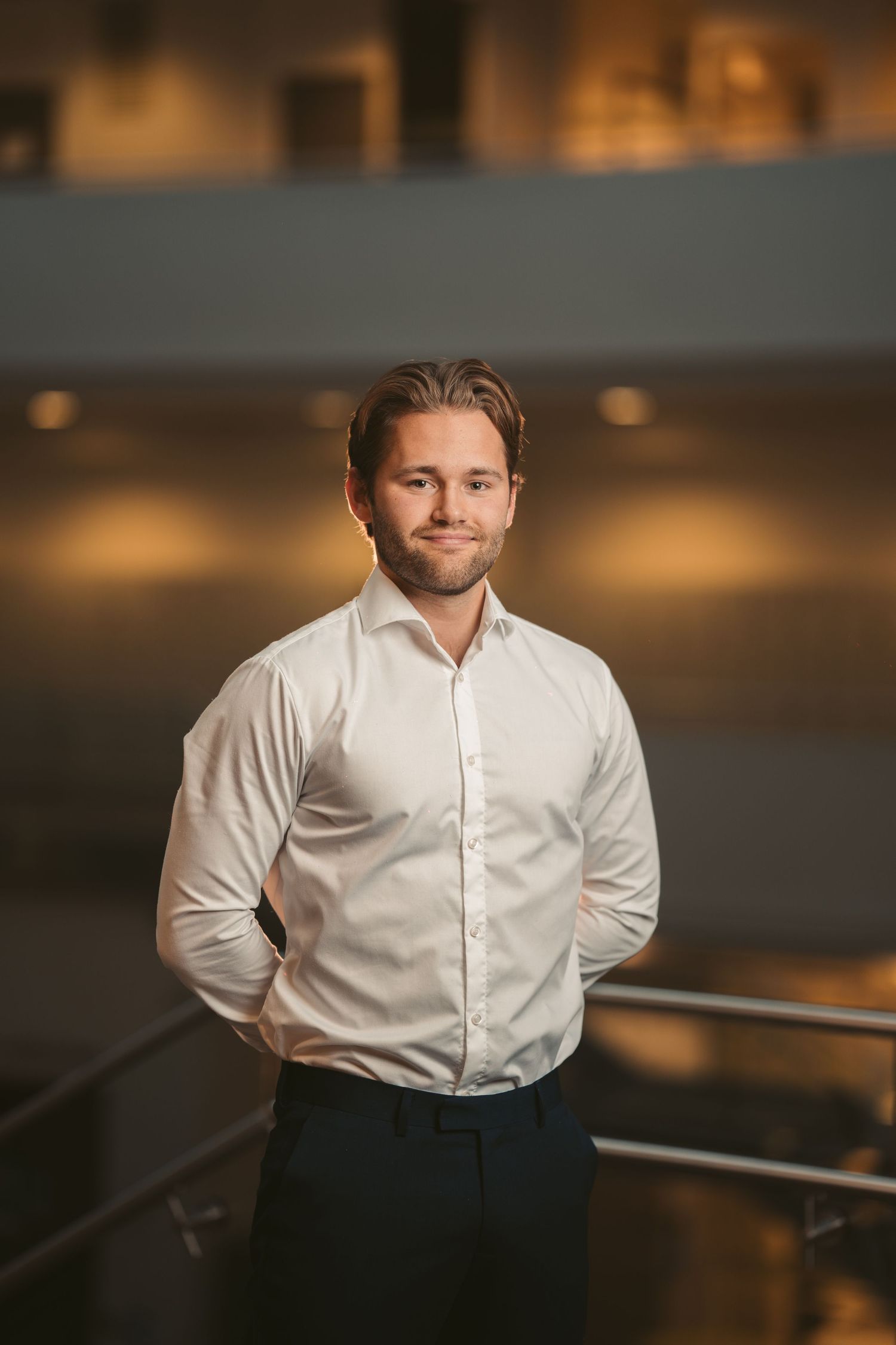 Professional portrait of someone in a white button-down shirt in an office setting.