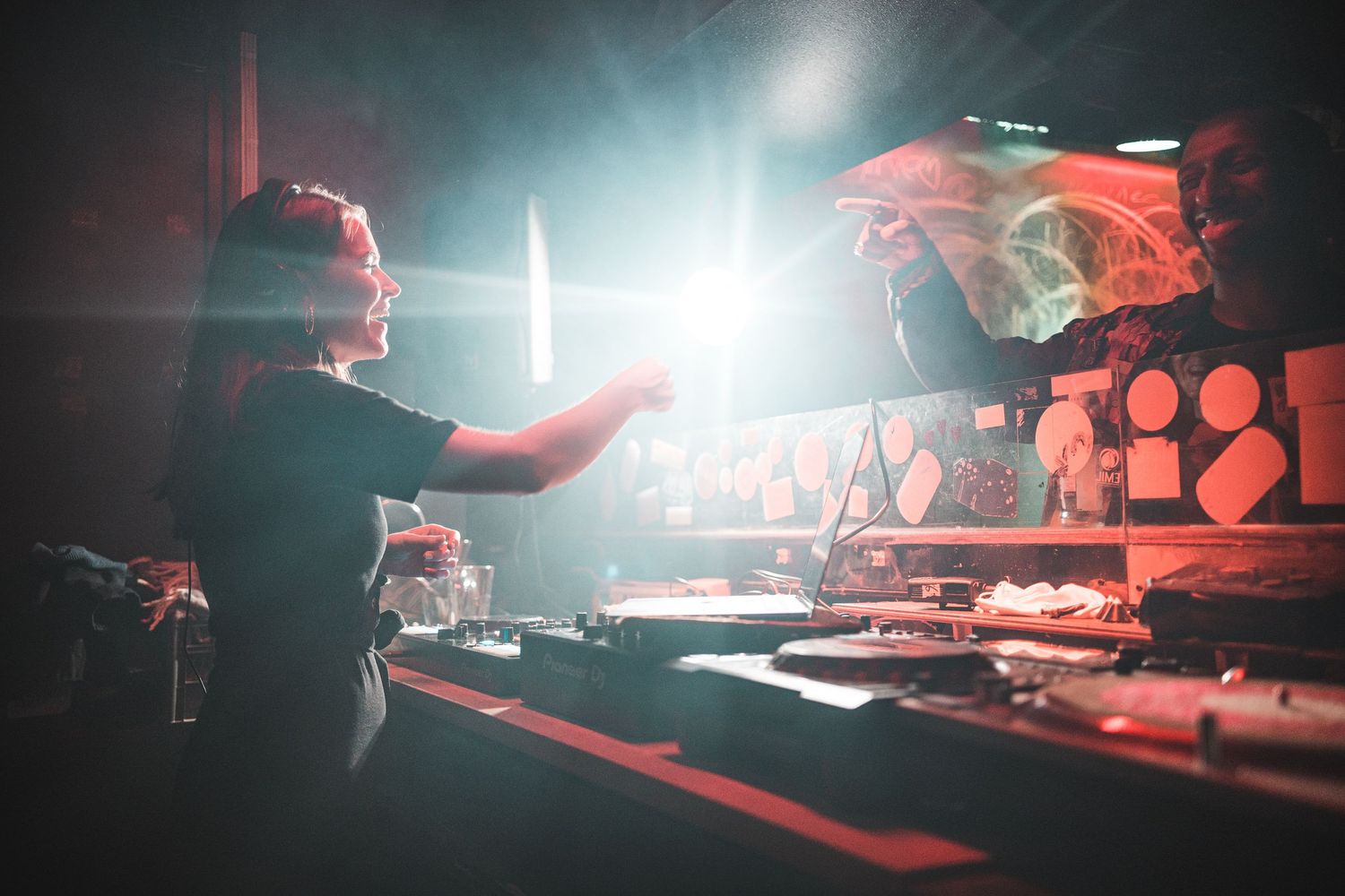 DJ performing at a nightclub with dramatic red lighting and smoke effects on stage.