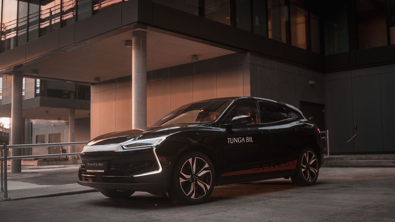 Modern electric cars lined up in a dark parking garage with dramatic lighting.