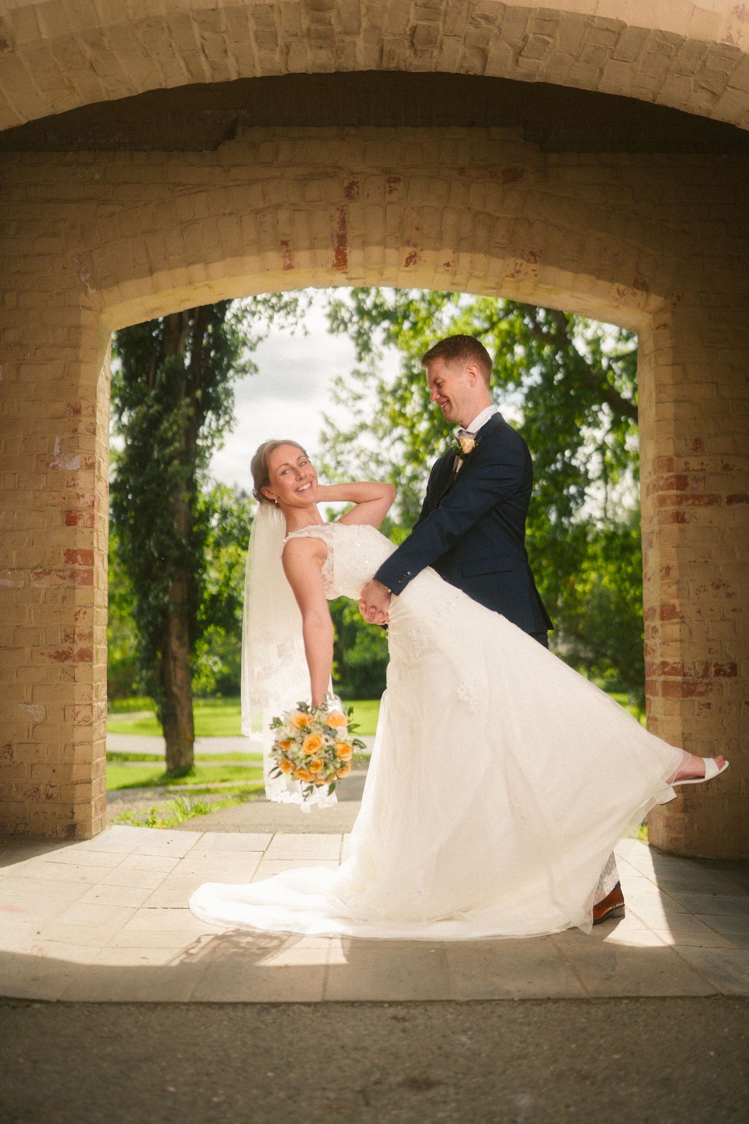 A series of romantic wedding poses under a stone archway with flowing white dress.