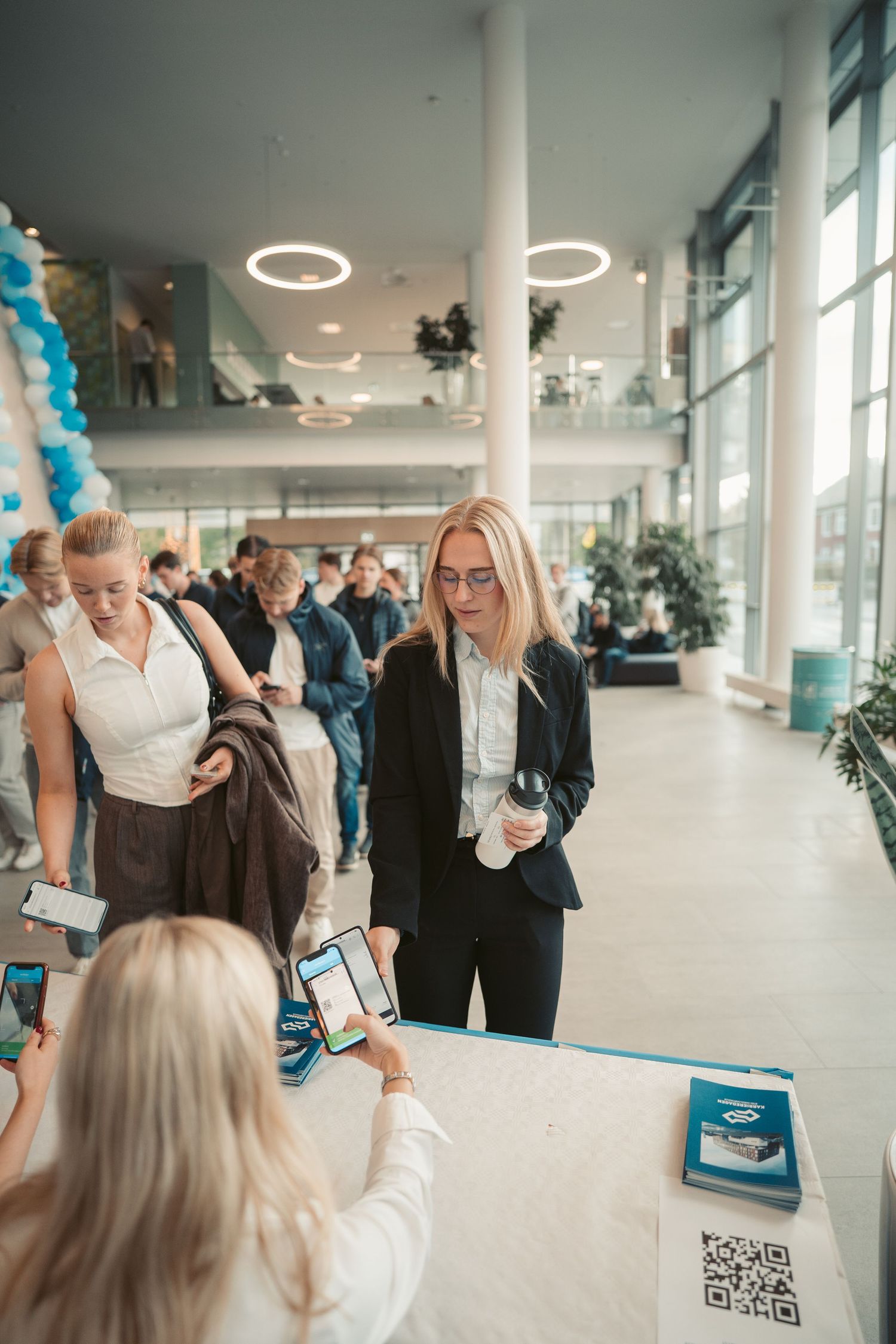 Modern event space with blue balloon decorations and guests mingling in a bright hallway.