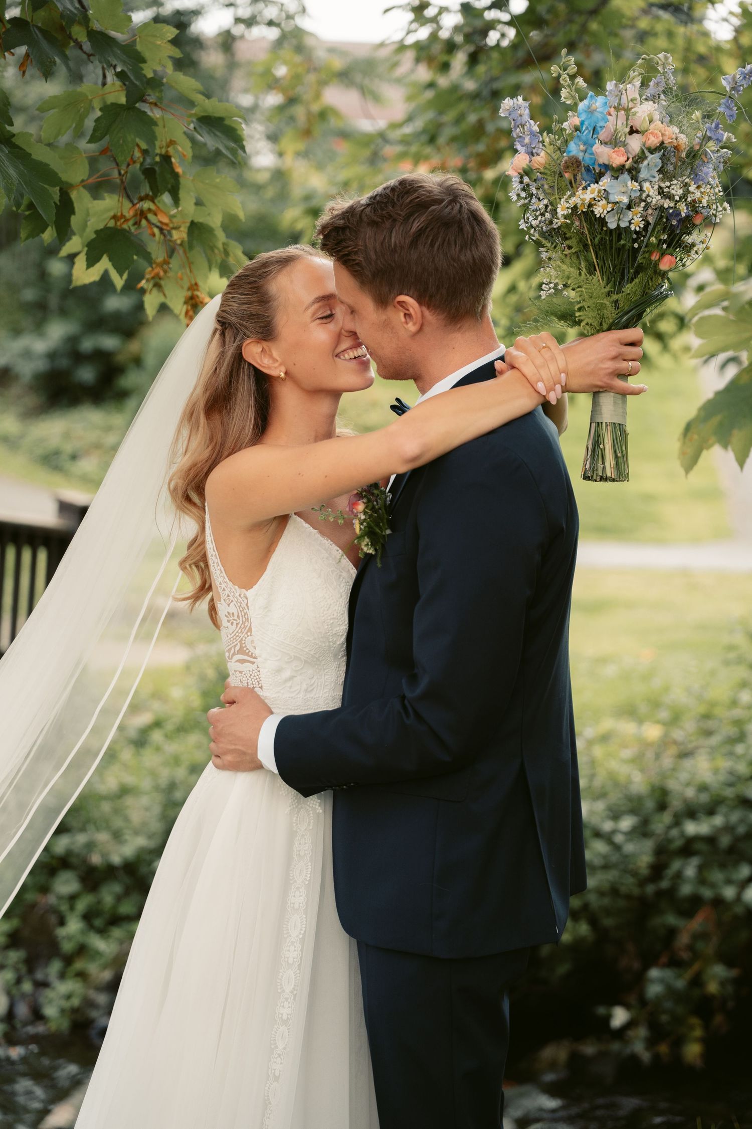 Romantic wedding portraits in garden setting with flowing veil and natural light.