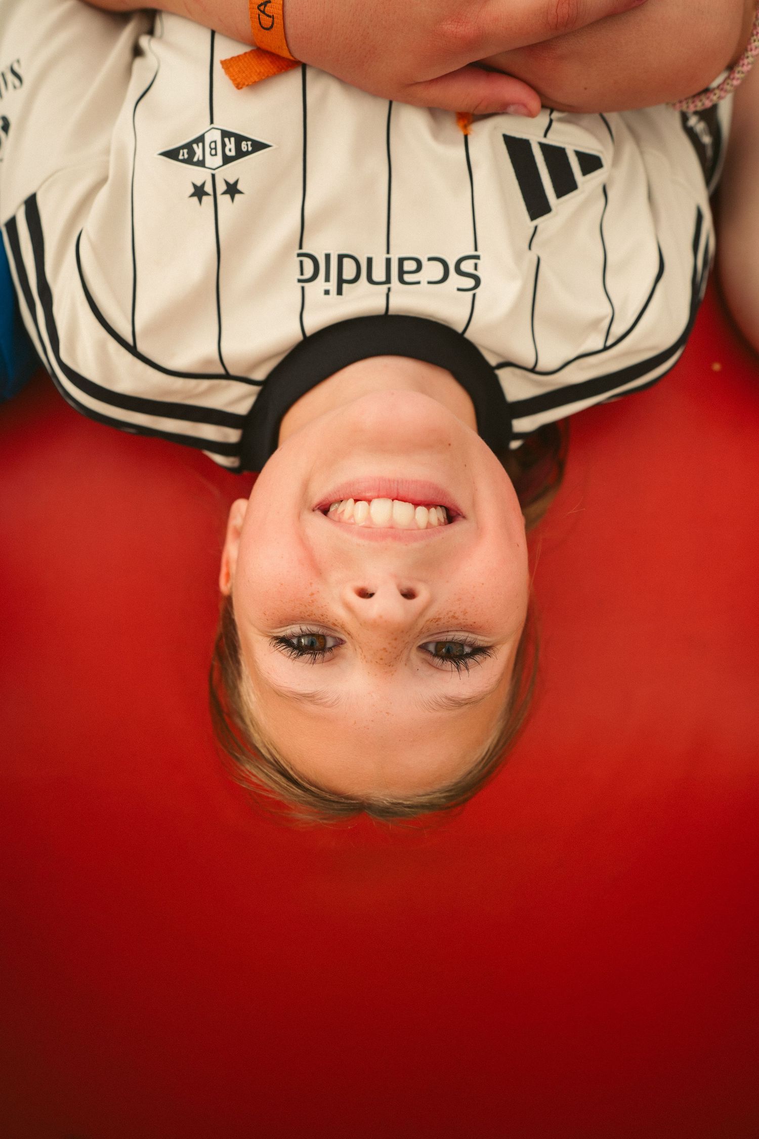 Creative upside down portrait against red background wearing a striped baseball jersey.
