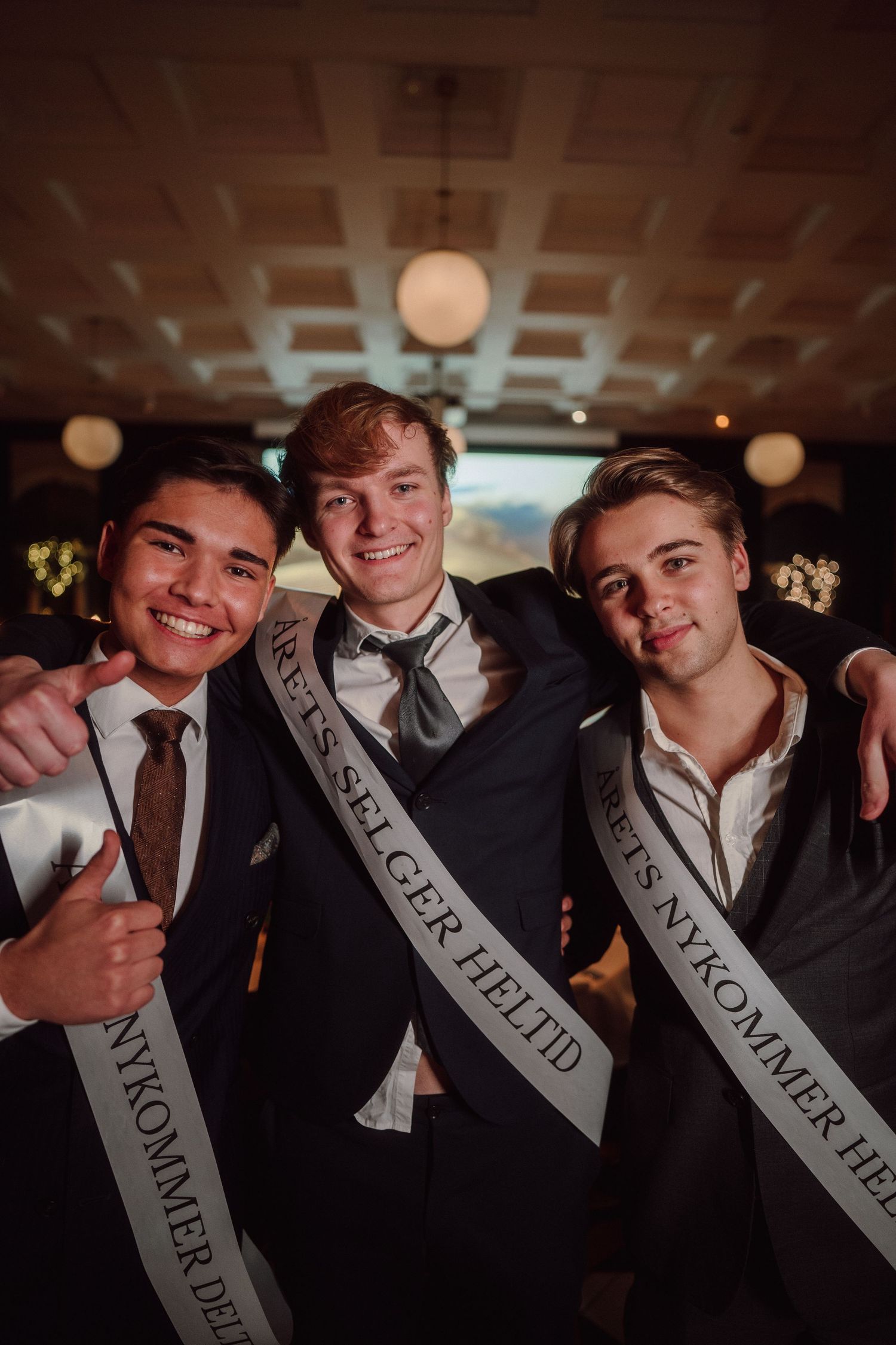 Group of formally dressed people wearing celebration sashes posing together at an event.