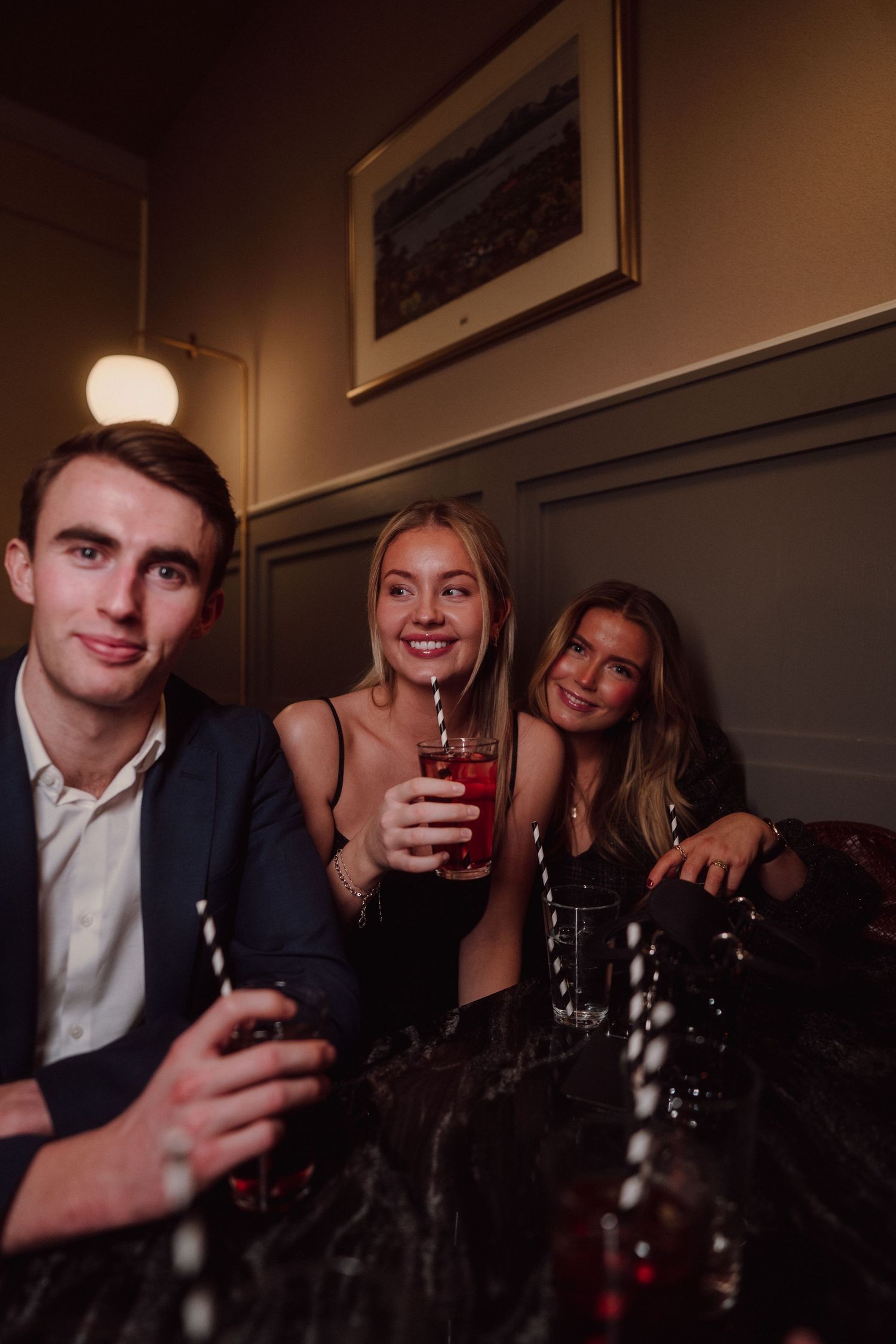 Friends gathered around a dark table enjoying drinks in a cozy restaurant setting.
