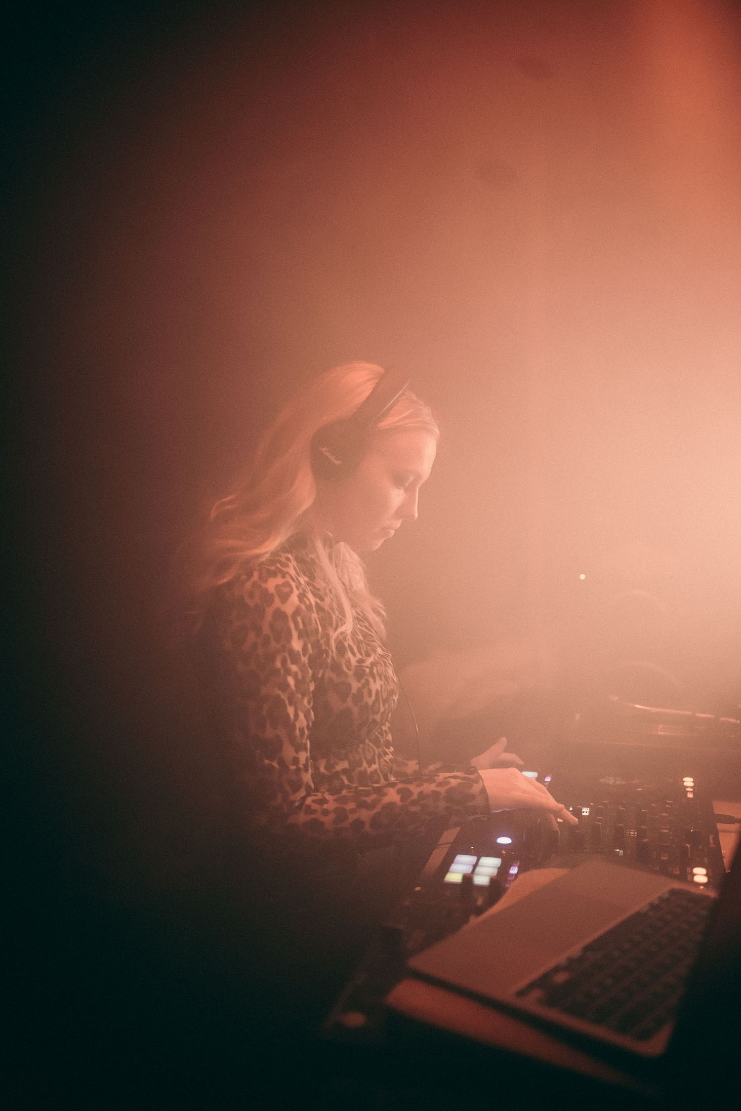 Atmospheric red-tinted photos of electronic music performance equipment in low light.