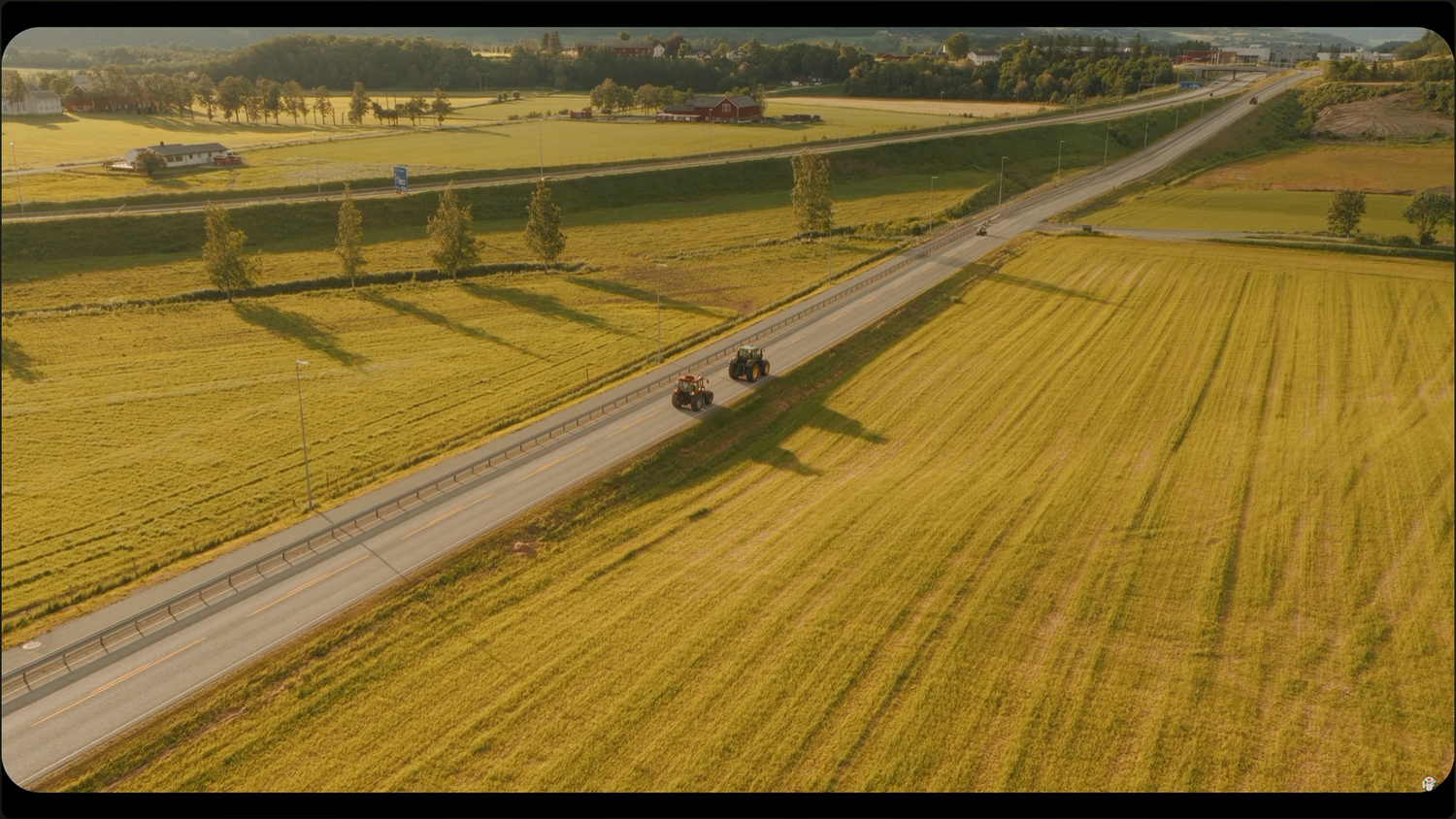 Aerial view of a rural road cutting through golden wheat fields with vehicles driving on a sunny day.