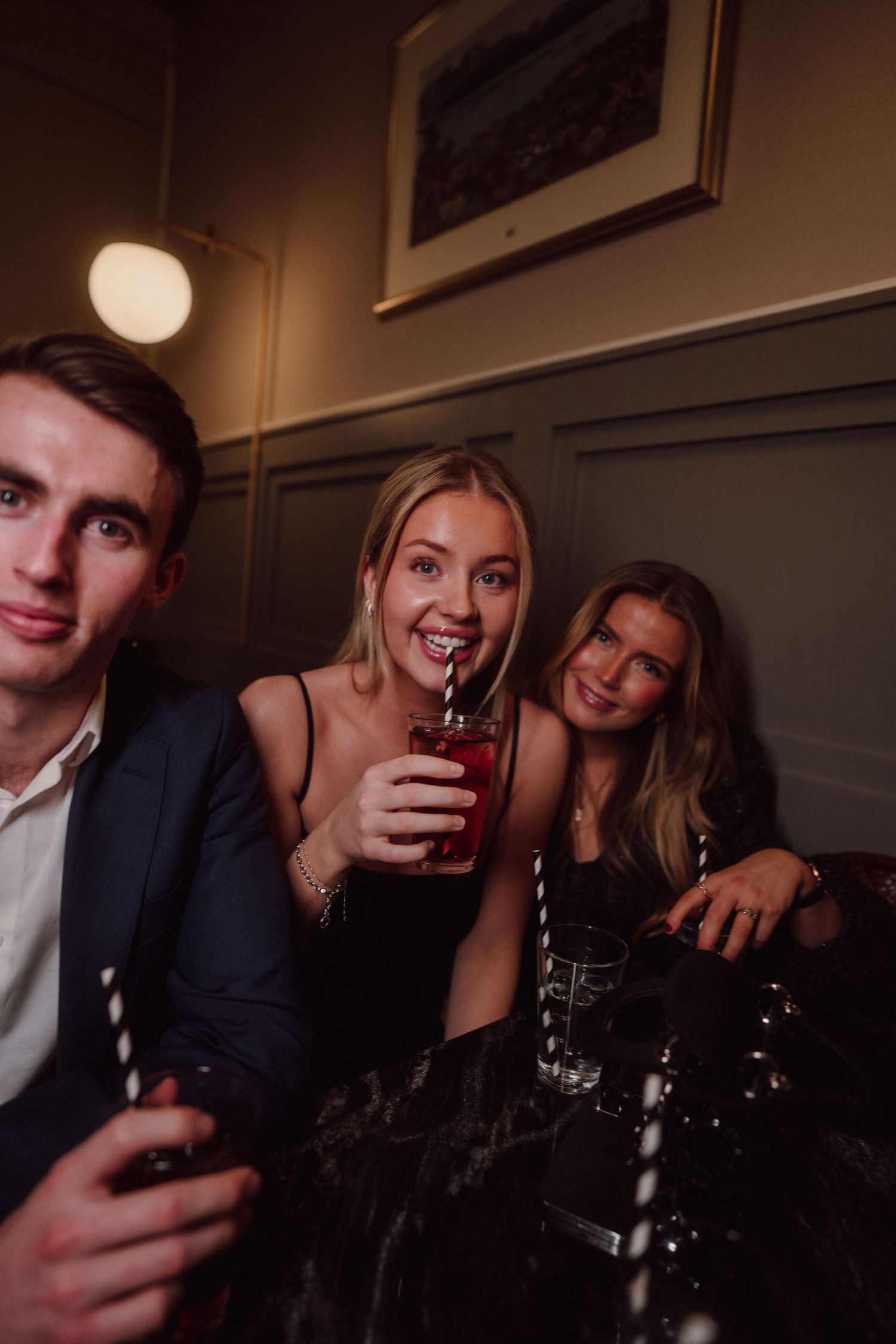 Group enjoying drinks and conversation at dimly lit bar setting.