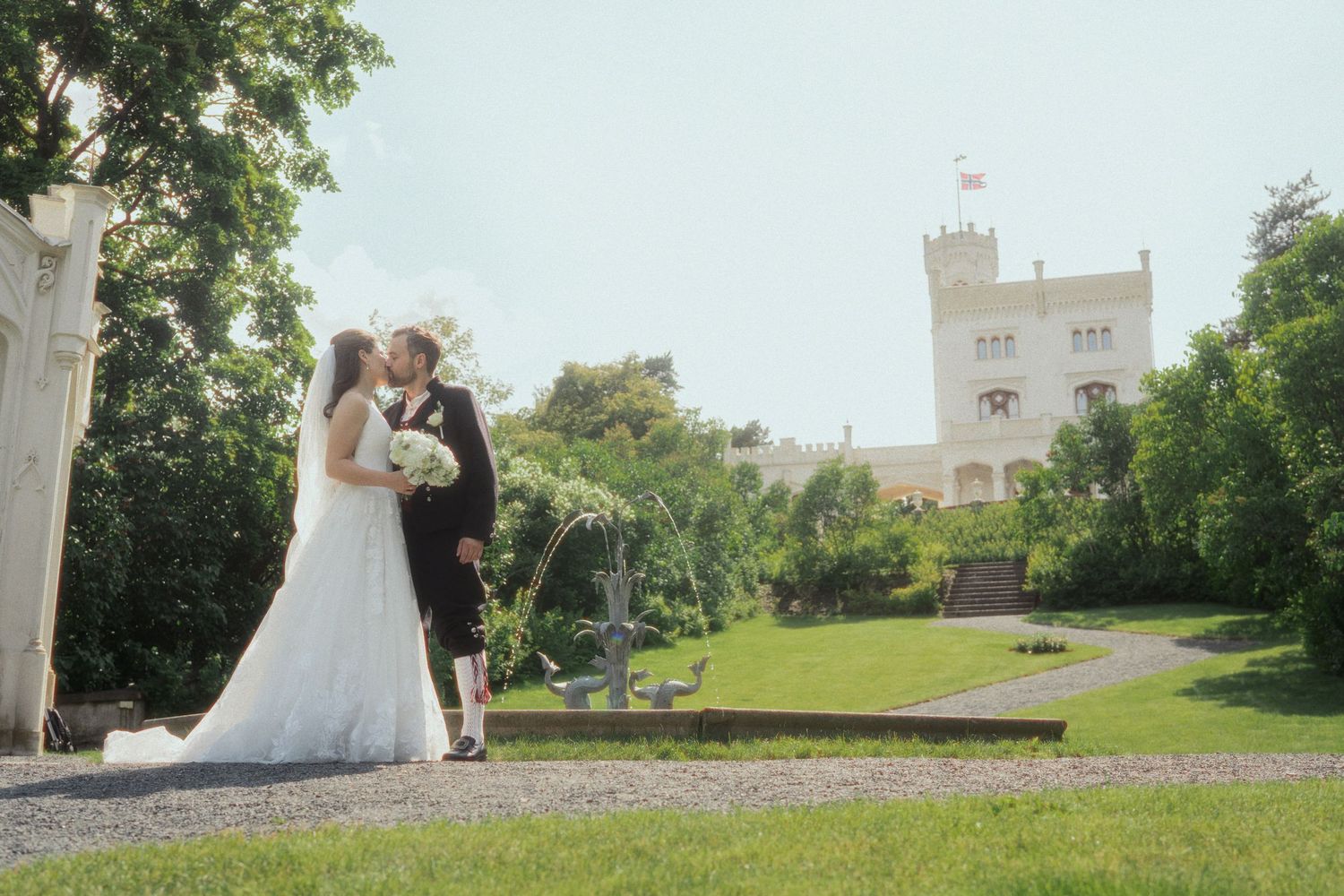 Wedding photos taken on castle grounds with white architecture and green landscaping.