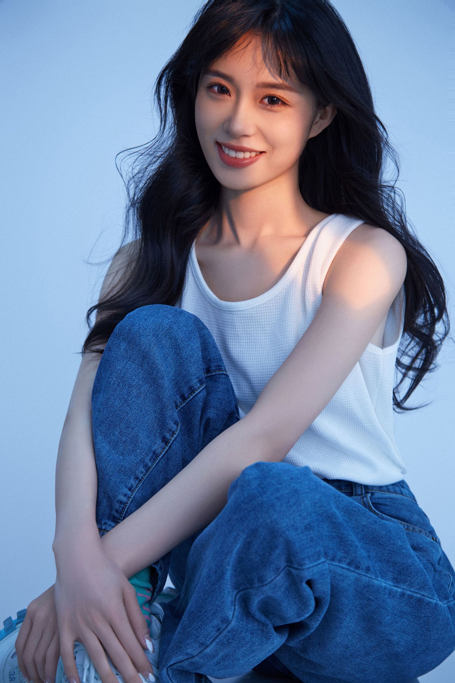 A casual portrait series showing someone in a white t-shirt and blue jeans against a light blue background.