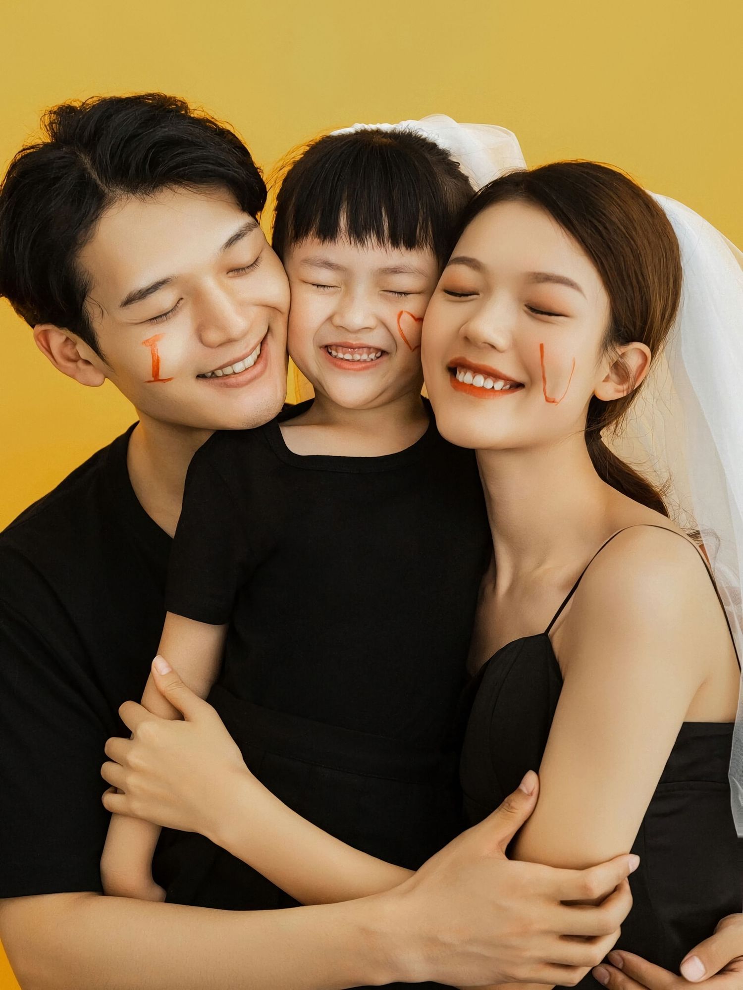 Three people wearing black outfits embrace and smile together in a warm yellow-toned photo series.