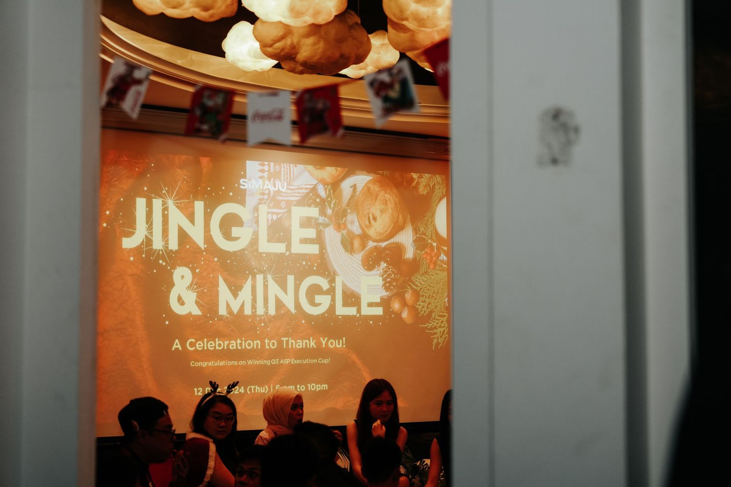 Jingle and Mingle celebration event with orange projection screen welcoming guests to a thank you party.