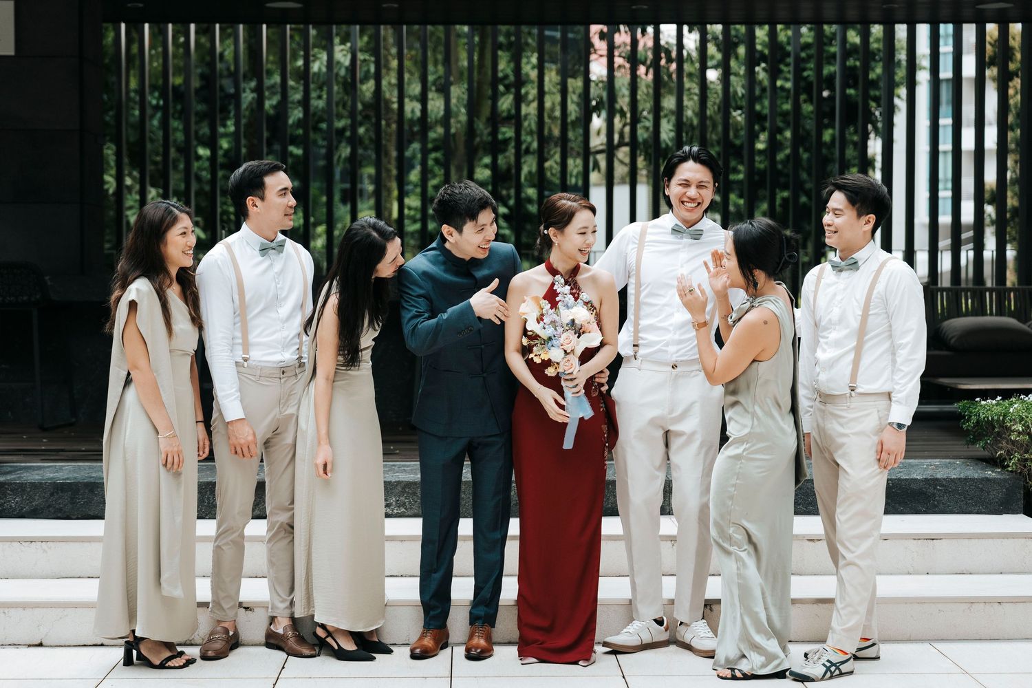 Group of friends in coordinated beige and burgundy outfits gather for a casual outdoor photo session.